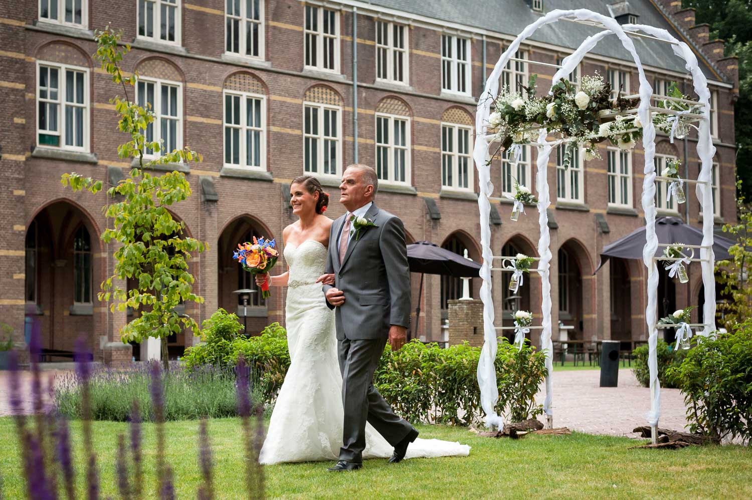 De bruid loopt met haar vader bij de aanvang van de ceremonie na