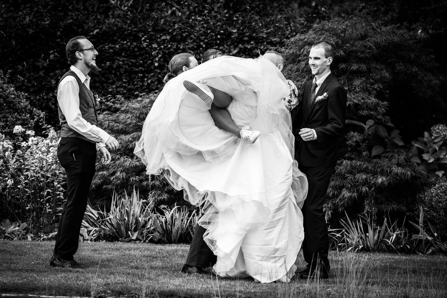 De bruid op de foto met haar broers, een grappige groepsfoto. Lekker spontaan, de bruid wordt opgetild door haar broers, maar het mislukt een beetje.