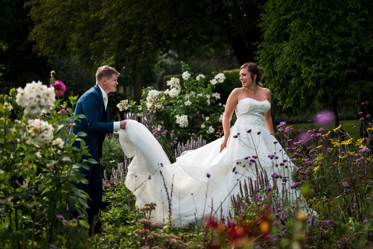 De bruidegom helpt de bruid met het goedleggen van haar trouwjurk. In de omgeving van Breda heb je veel mooie plekjes om gave foto's te maken. Dit kan in de natuur maar ook midden in Breda.