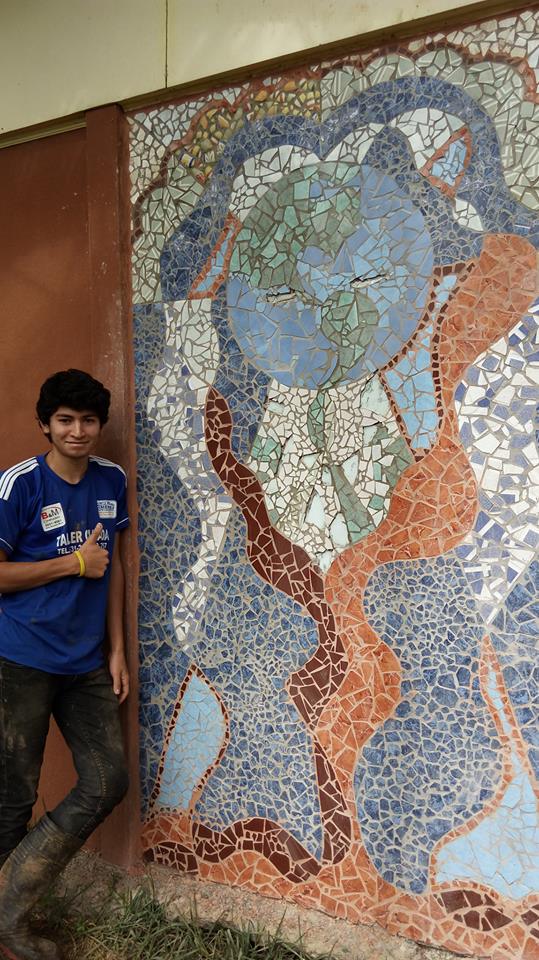  A volunteer, smiling in front of the finished piece, who helped Omar finalize the mural by filling in the spaces between the tiles! 