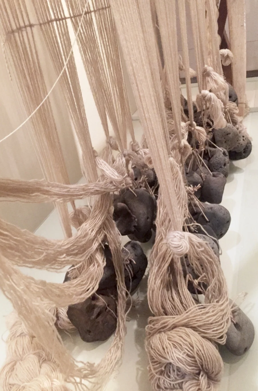 Loom weights tied onto the warp threads on a warp-weighted loom at the National Museum of Iceland. The Woven Road.