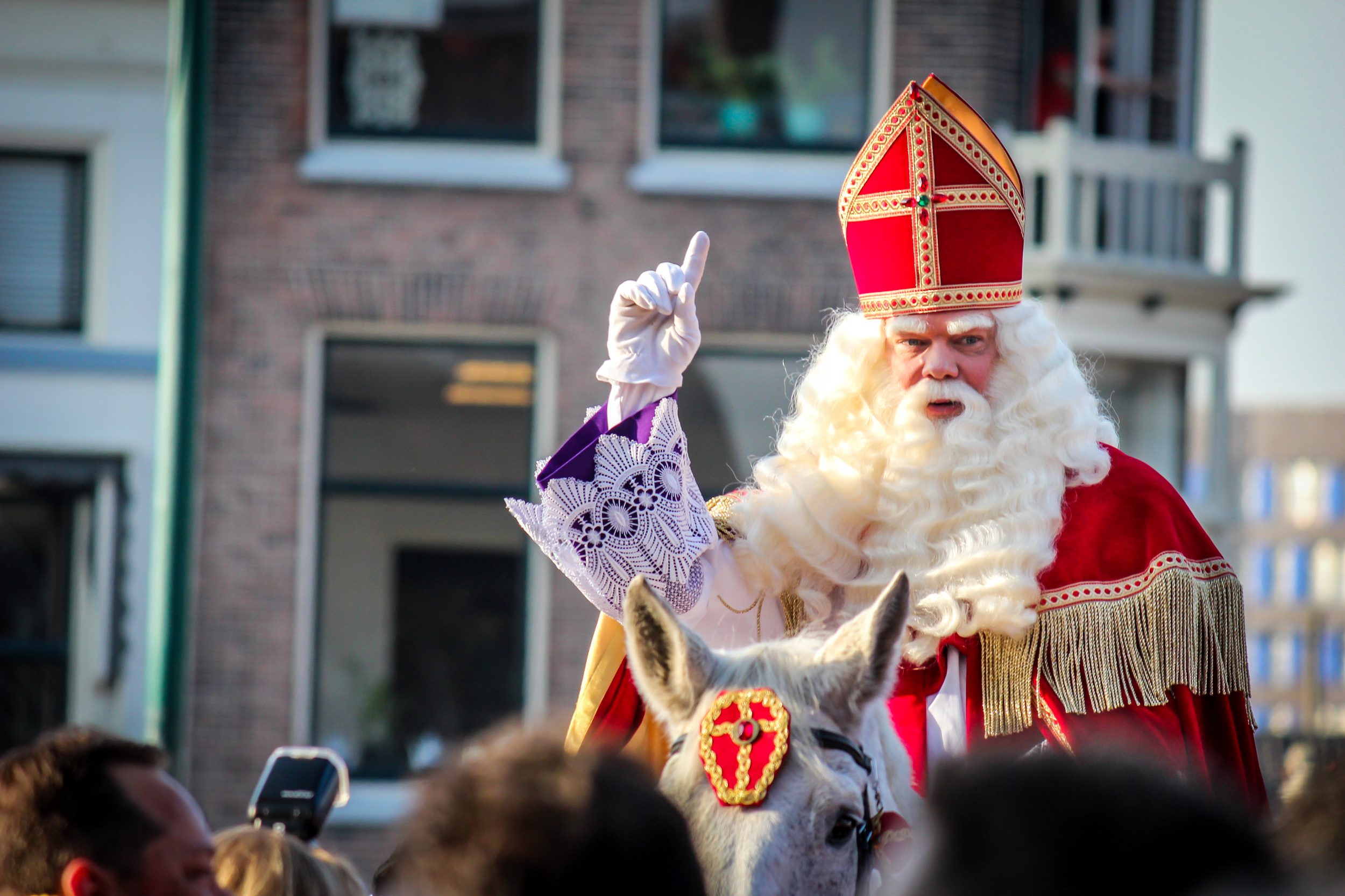 Sinterklaas rides through town on top of his classic white horse while waving to the crowd.