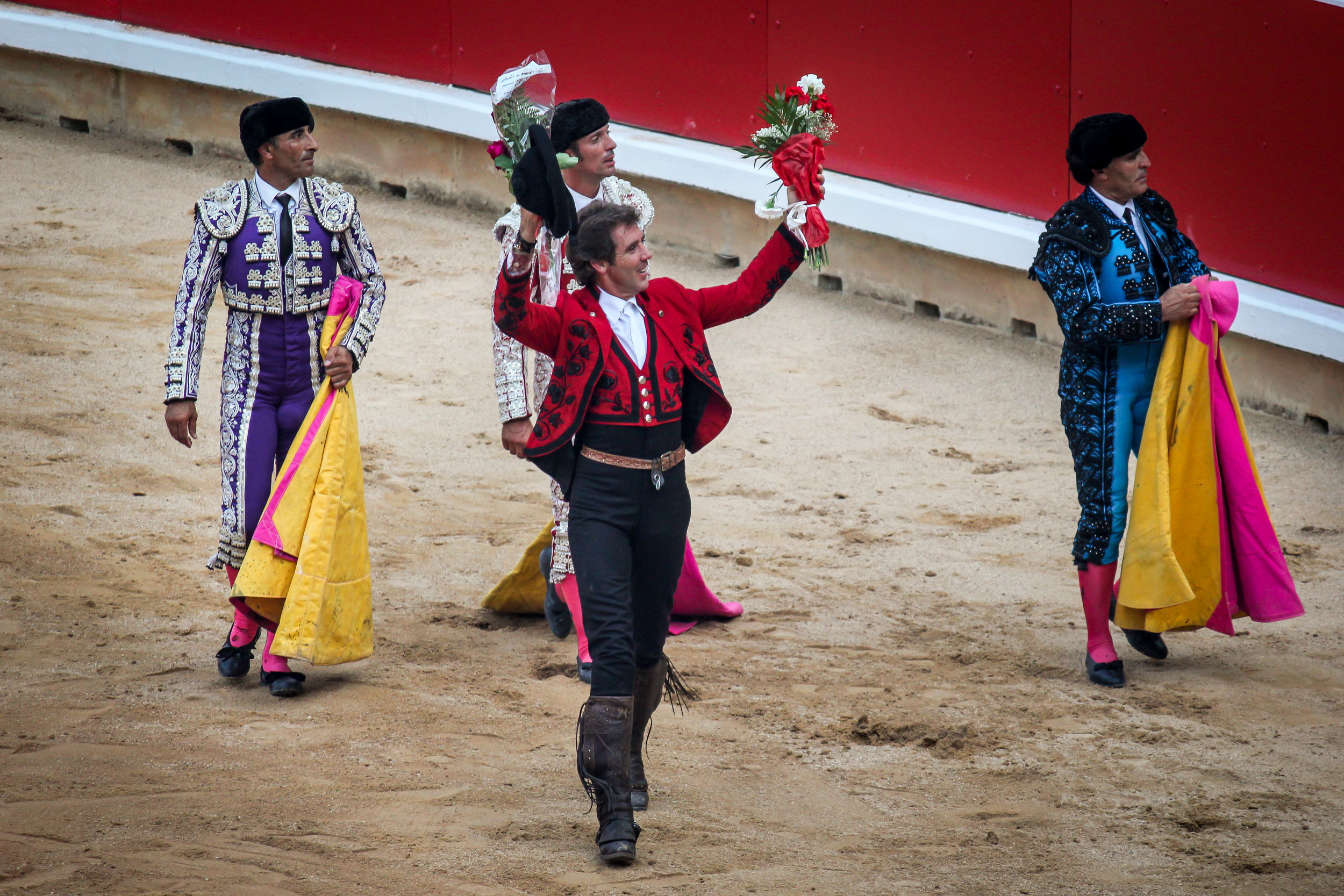 A matador celebrates a clean kill while receiving gifts thrown into the ring by spectators.