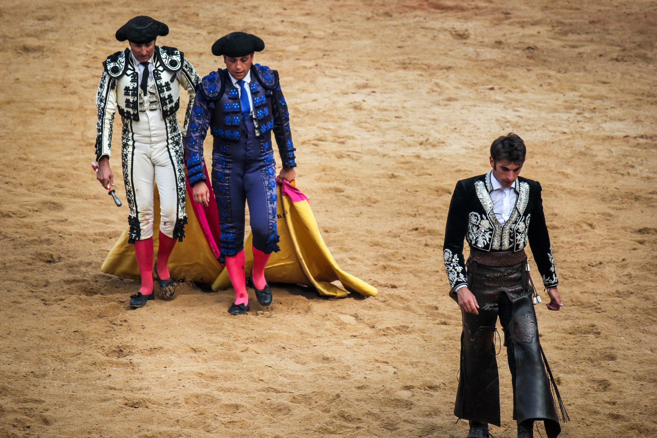 A poor fight is one where the bull suffers due to mistakes and inaccurate moves. Here a matador and his helpers walk away with shame and the crowd boos at their efforts.