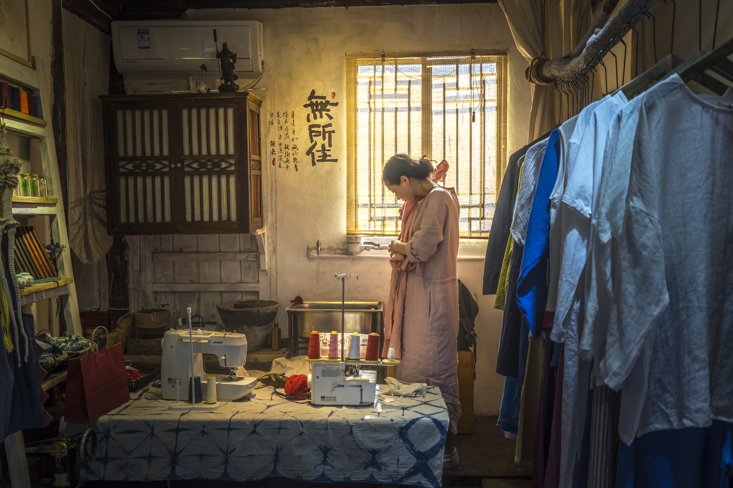  This photo was taken in Zhujiajiao, a city close to Shanghai. While walking through the narrow streets I peered into the opening of a small shop. There I saw a woman peacefully folding some clothes. I had to capture this scene as it showed various m