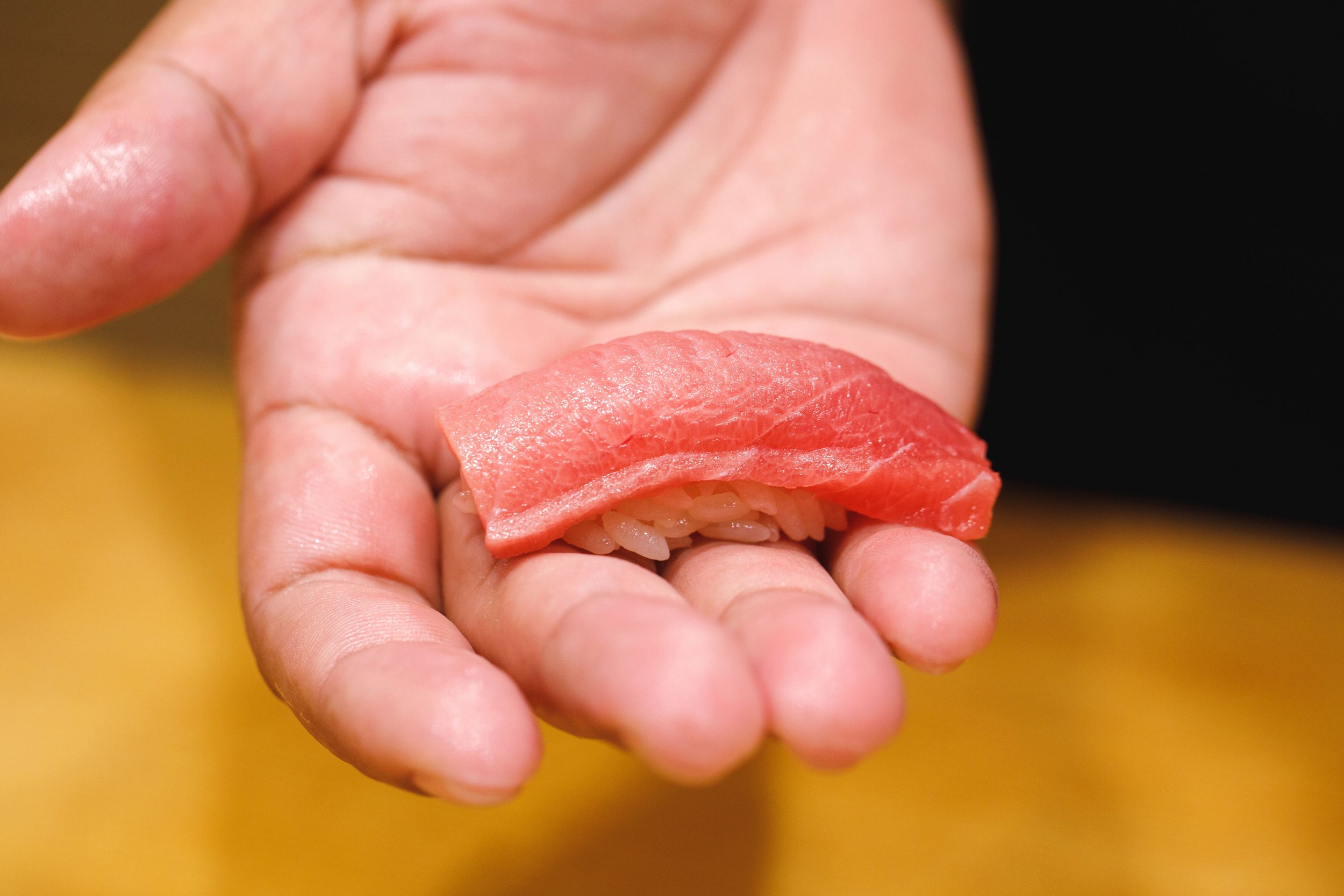 Chef holding a piece of tuna nigiri