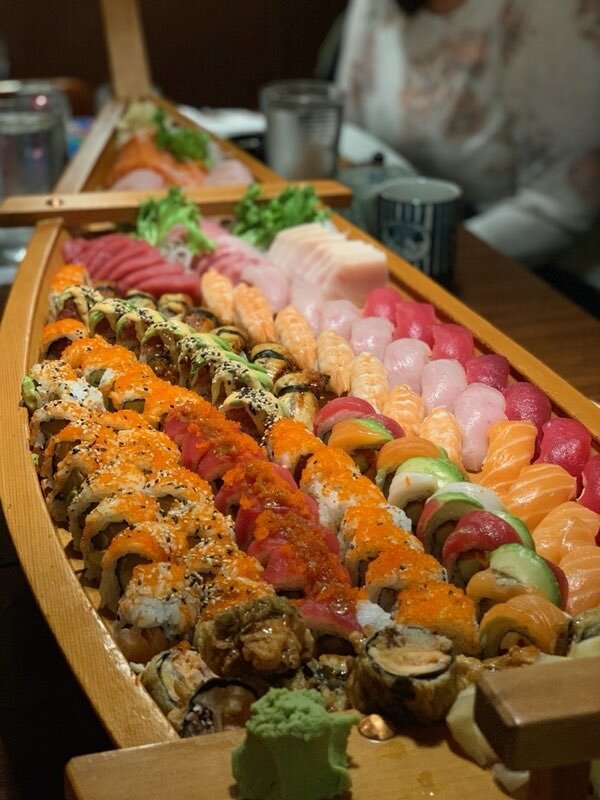 Variety of sushi rolls, nigiri, and sashimi on a boat