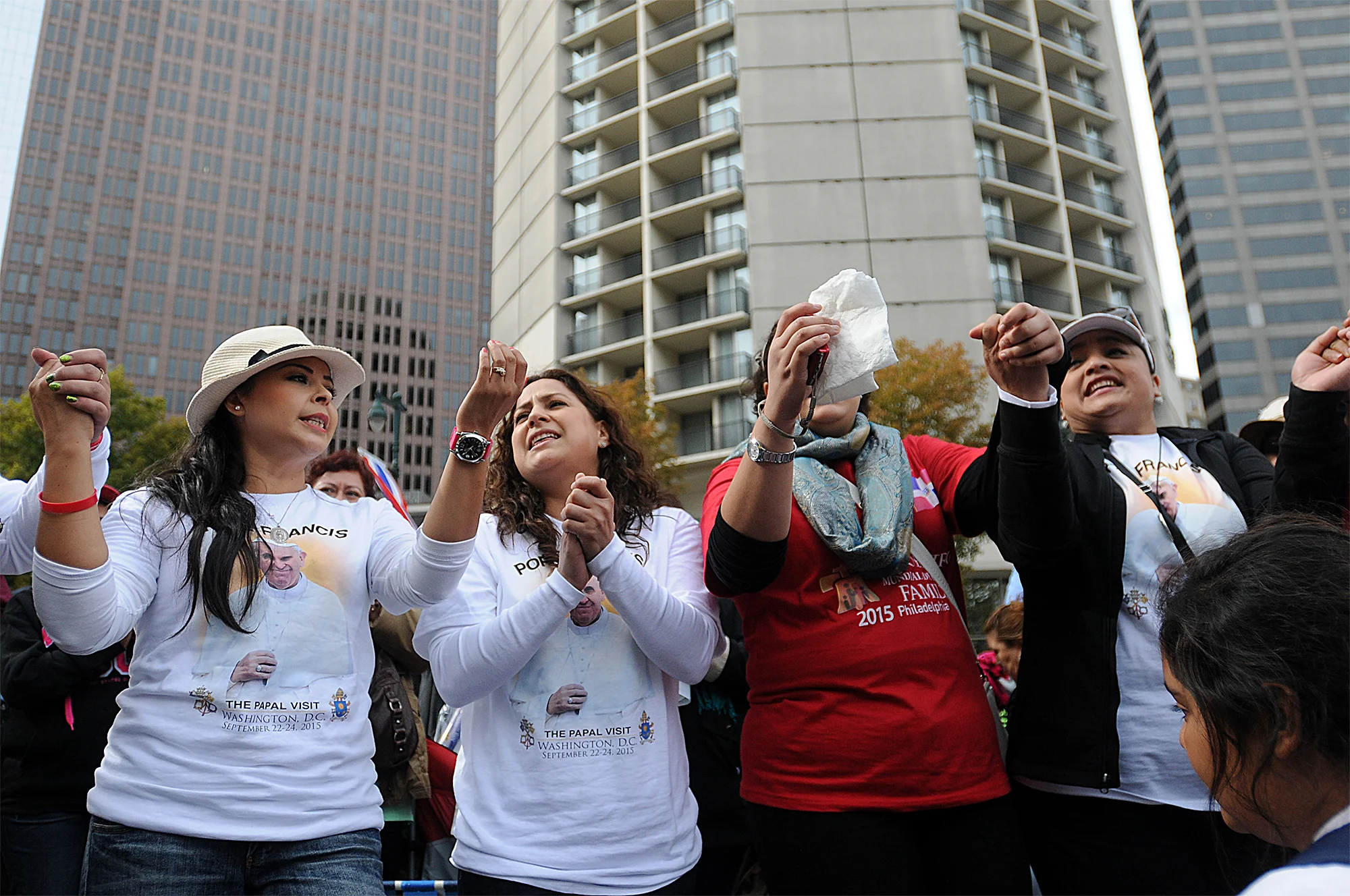  From left: Nora Garcia, Rocio Dardon, Laura Gonzalez and Noriza Escalante, all of Los Angeles, California, sing a song about Pope Francis while waiting to see him arrive via jumbotrons to Cathedral Basilica of Saints Peter and Paul on the Ben Frankl
