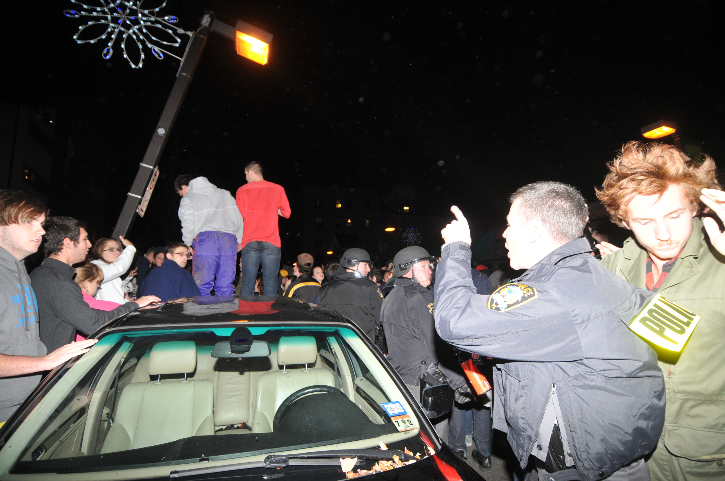  A policeman yells at rioters standing on top of a car in Beaver Canyon Wednesday night. 