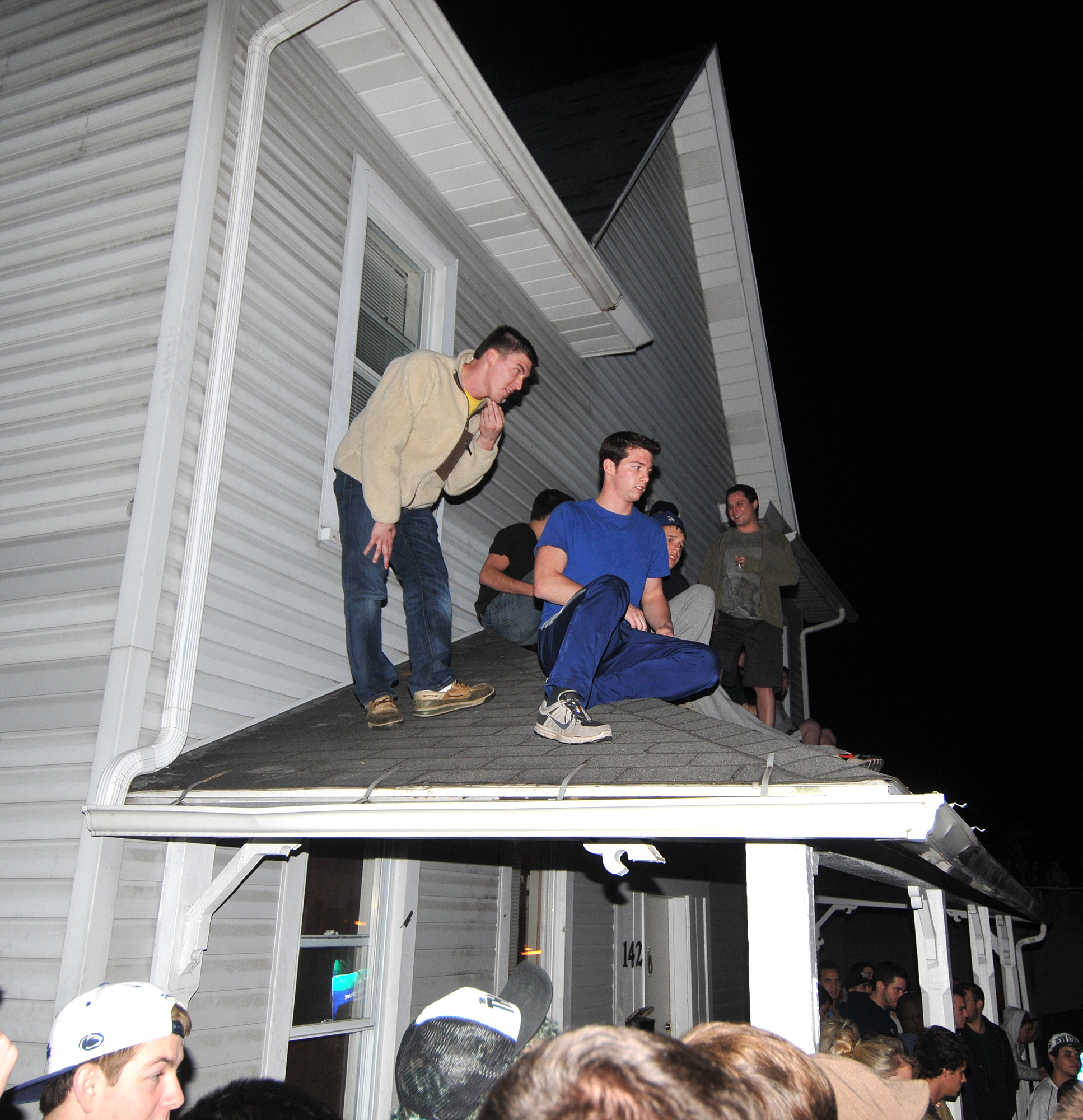  Students sit on the roof of a house at the corner of Beaver and Pugh Street on Wednesday night during the riots. 