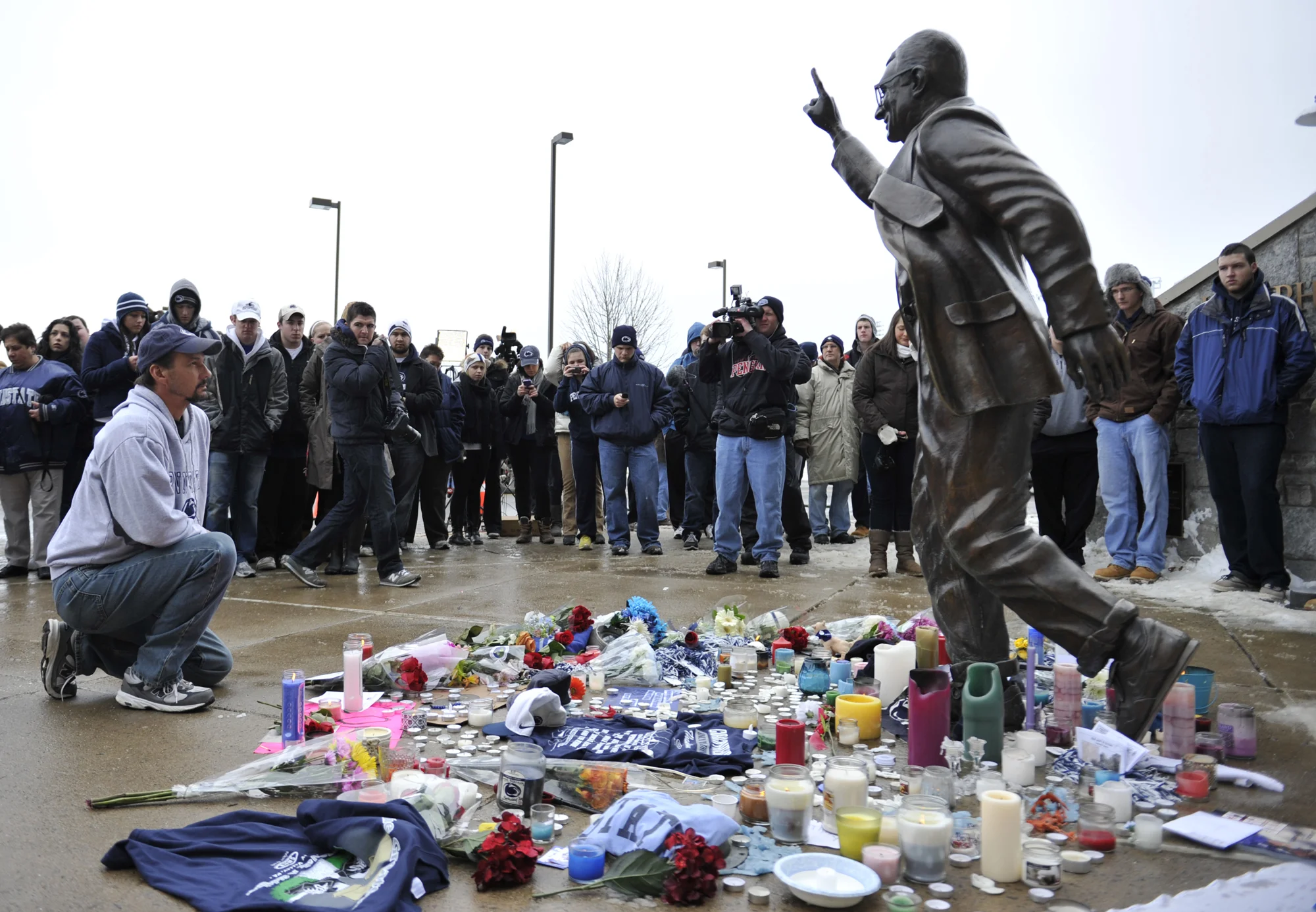 A mourner kneels in front of the Joe Paterno statue on Sunday, Jan. 22, 2012 where a crowd had gathered upon hearing news of his death.
