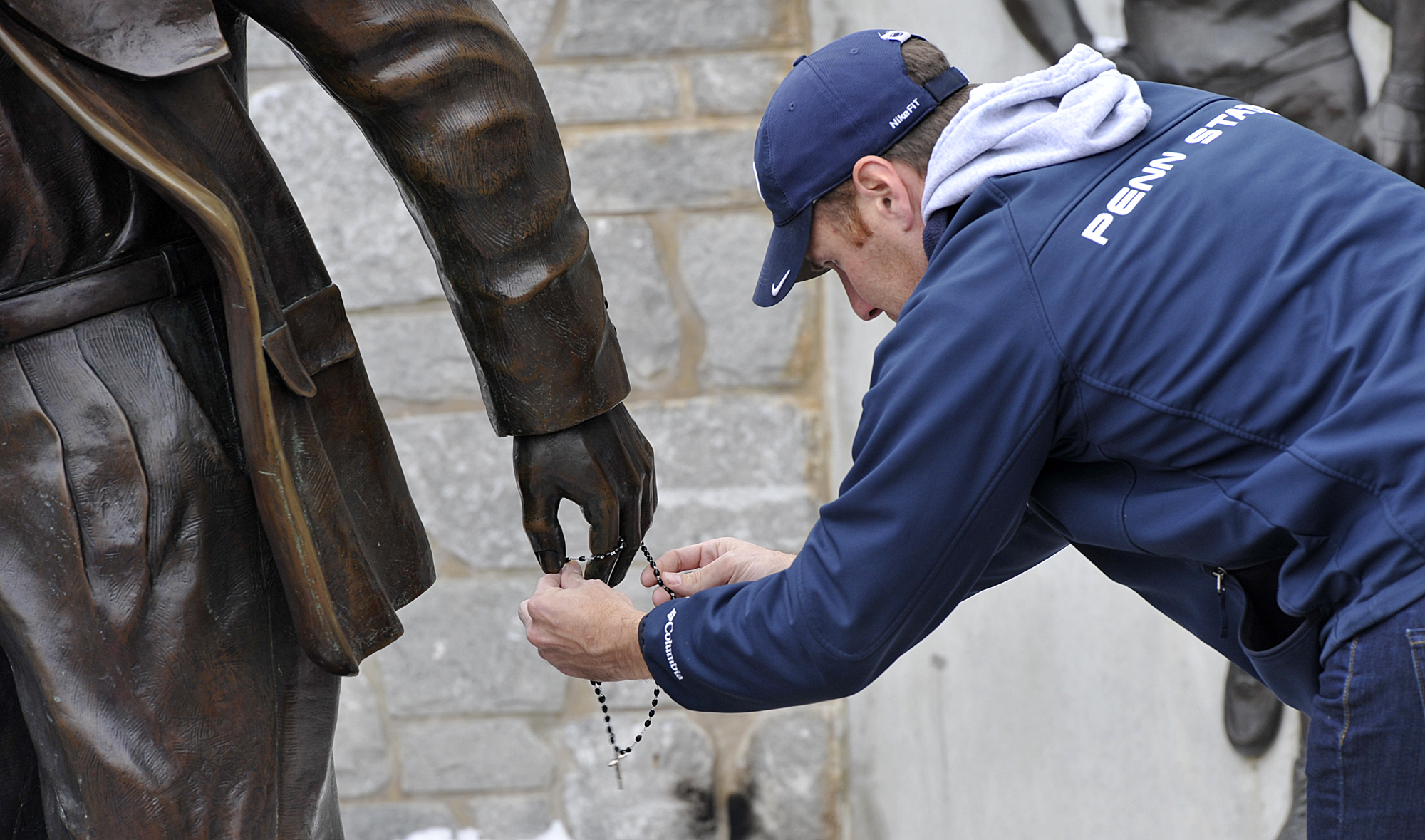  A mourner places a rosary around the hand of the Joe Paterno statue on Sunday, Jan. 22, 2011 outside of Beaver Stadium. A crowd had gathered after hearing the news that Paterno had passed away in the morning. 