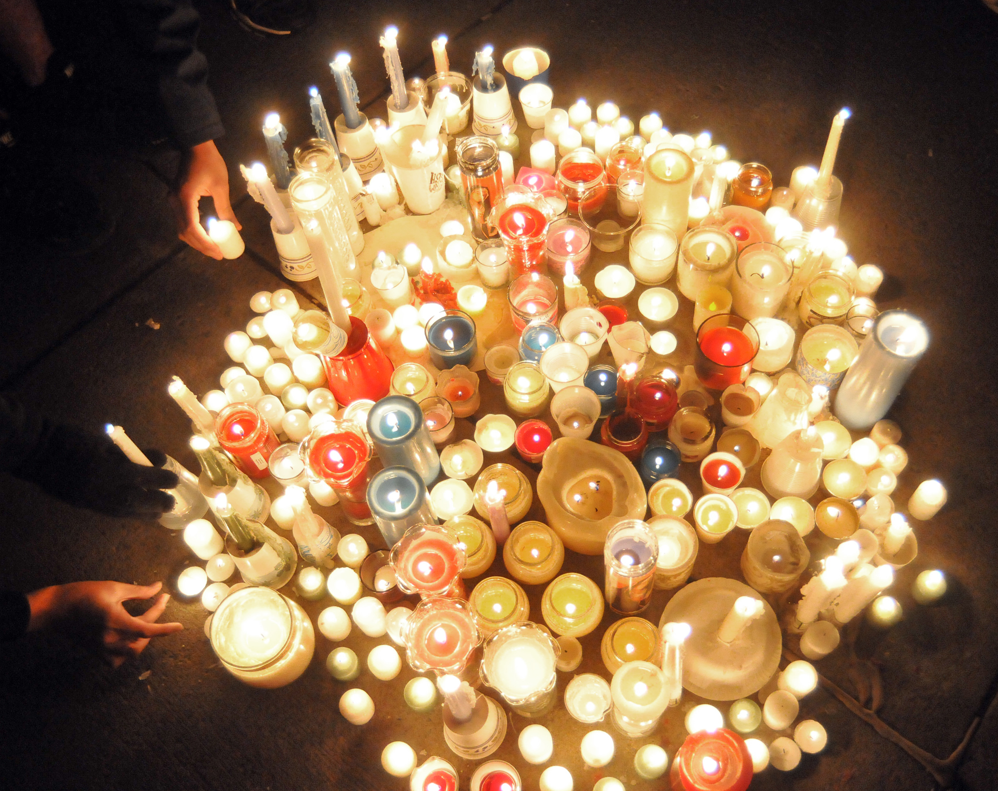  Hands add candles to a small circle on the Old Main patio on Friday, Nov. 11, 2011 at a vigil for victims of sexual assault. 