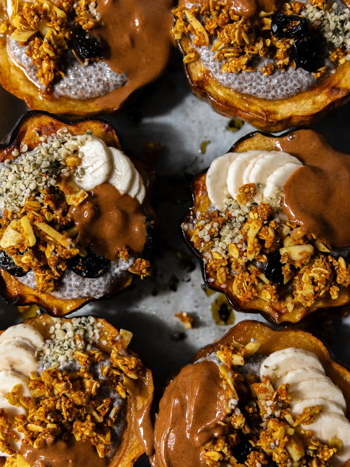 Maple-roasted acorn squash breakfast bowls filled with pumpkin spice chia pudding and topped with Garden Granola Carrot Turmeric, hemp seeds, and sliced bananas.