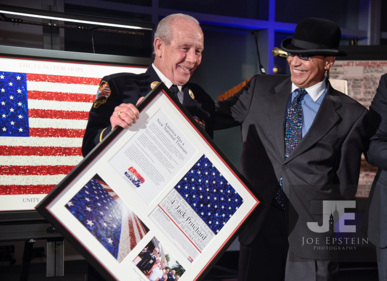 Marcos Antonio presents Captain Jack Pritchard, legendary NYC firefighter and star #4 on the Flag For Hope, with his serigraph and certificate of authenticity
