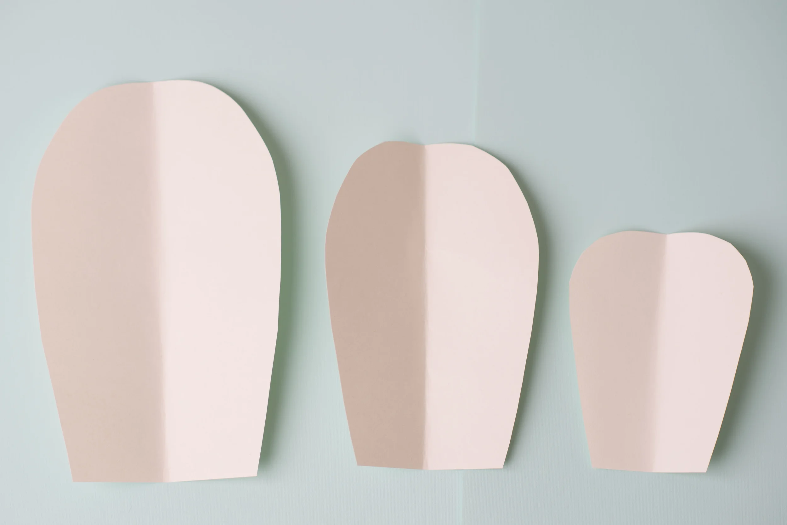 Create your petal templates -- one small, medium, and large for each style of flower. &nbsp;Fold your template paper in half and cut out the shape of a petal. &nbsp;Try different styles with rounded petals, pointed petals, and ruffled petals.