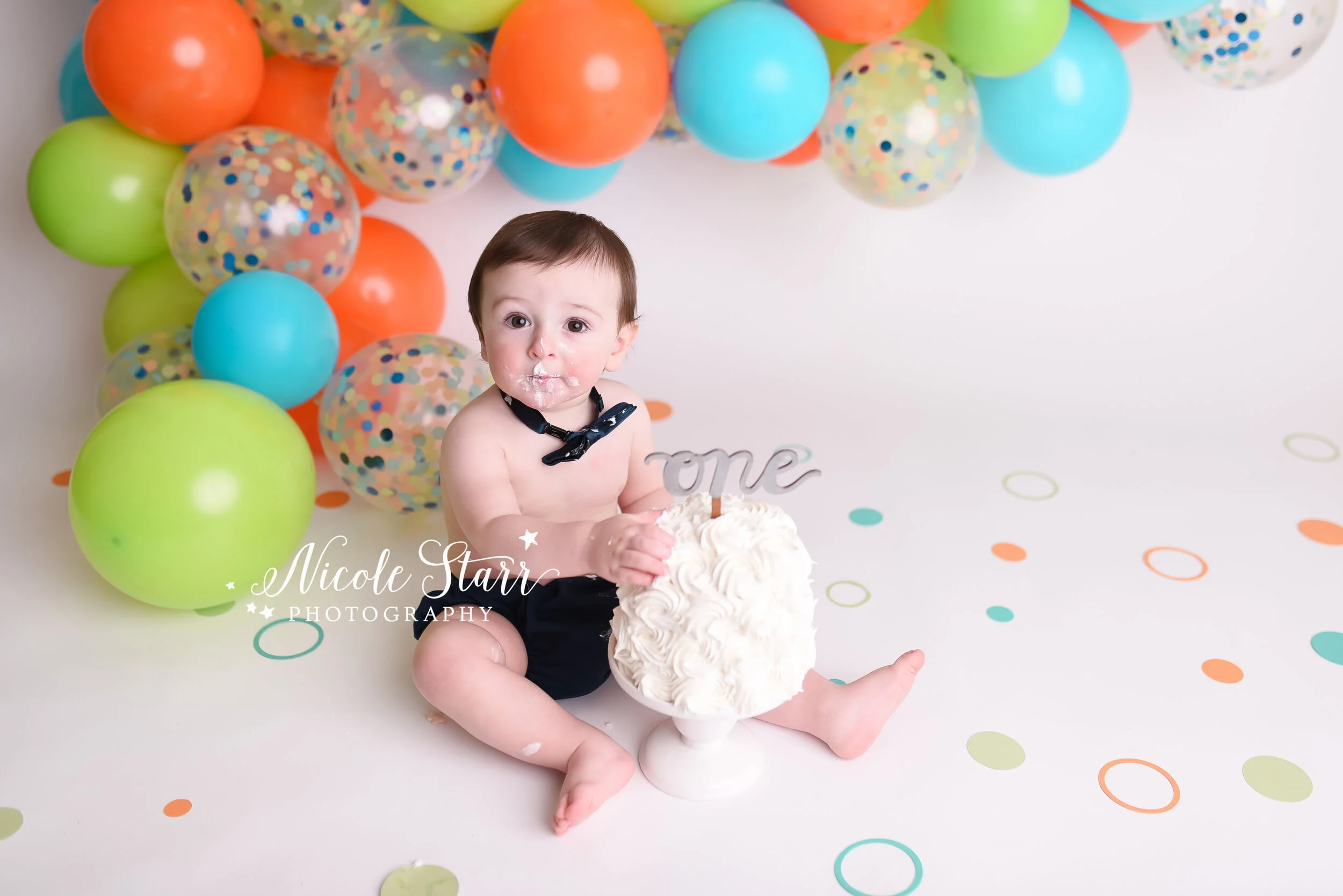 Bright and bold balloon garland cake smash with orange, green, and blue by Nicole Starr Photography | Saratoga Springs Cake Smash Photographer | Boston Cake Smash Photographer | Saratoga Springs Family Photographer | Boston Family Photographer | Del…