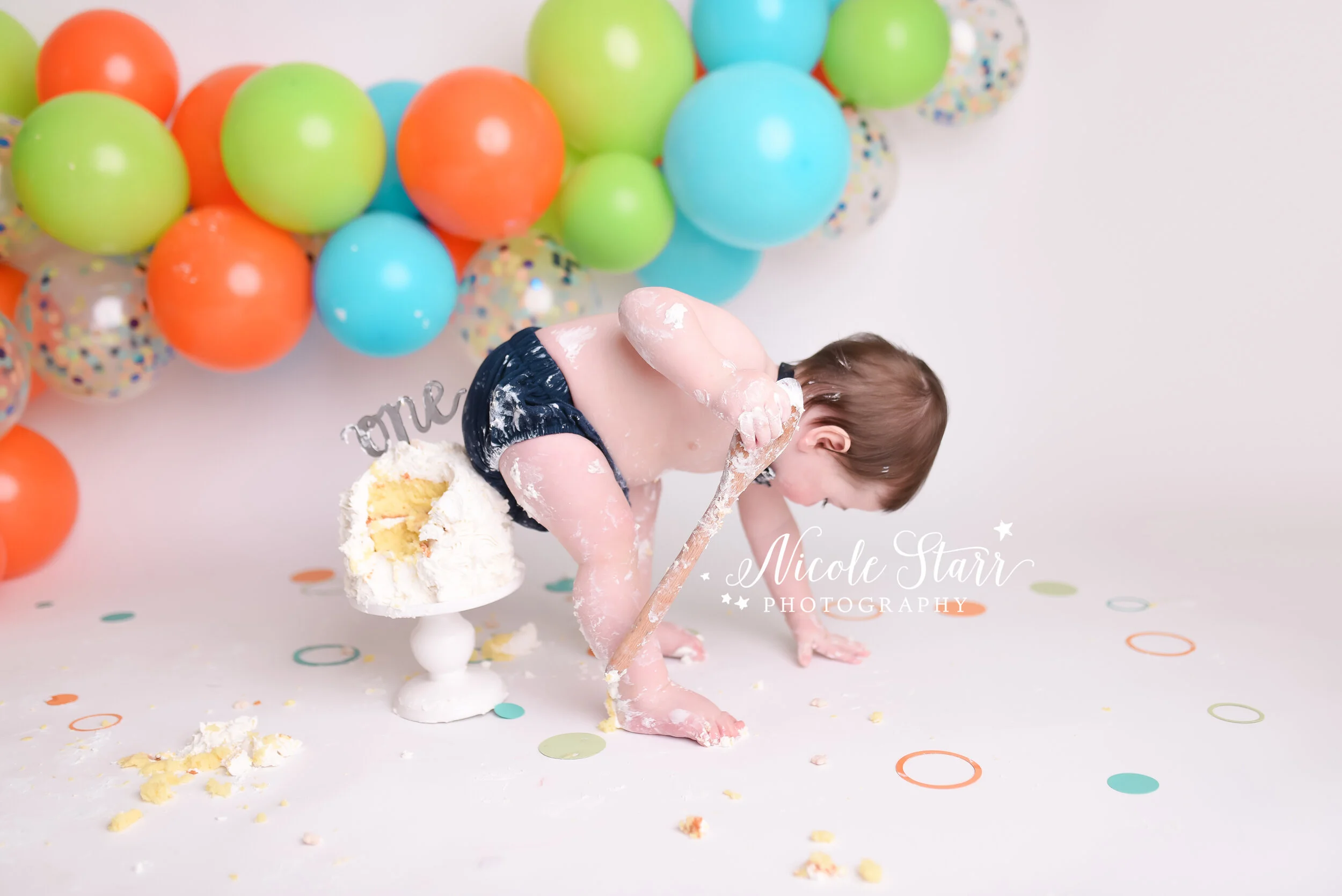 Bright and bold balloon garland cake smash with orange, green, and blue by Nicole Starr Photography | Saratoga Springs Cake Smash Photographer | Boston Cake Smash Photographer | Saratoga Springs Family Photographer | Boston Family Photographer | Del…