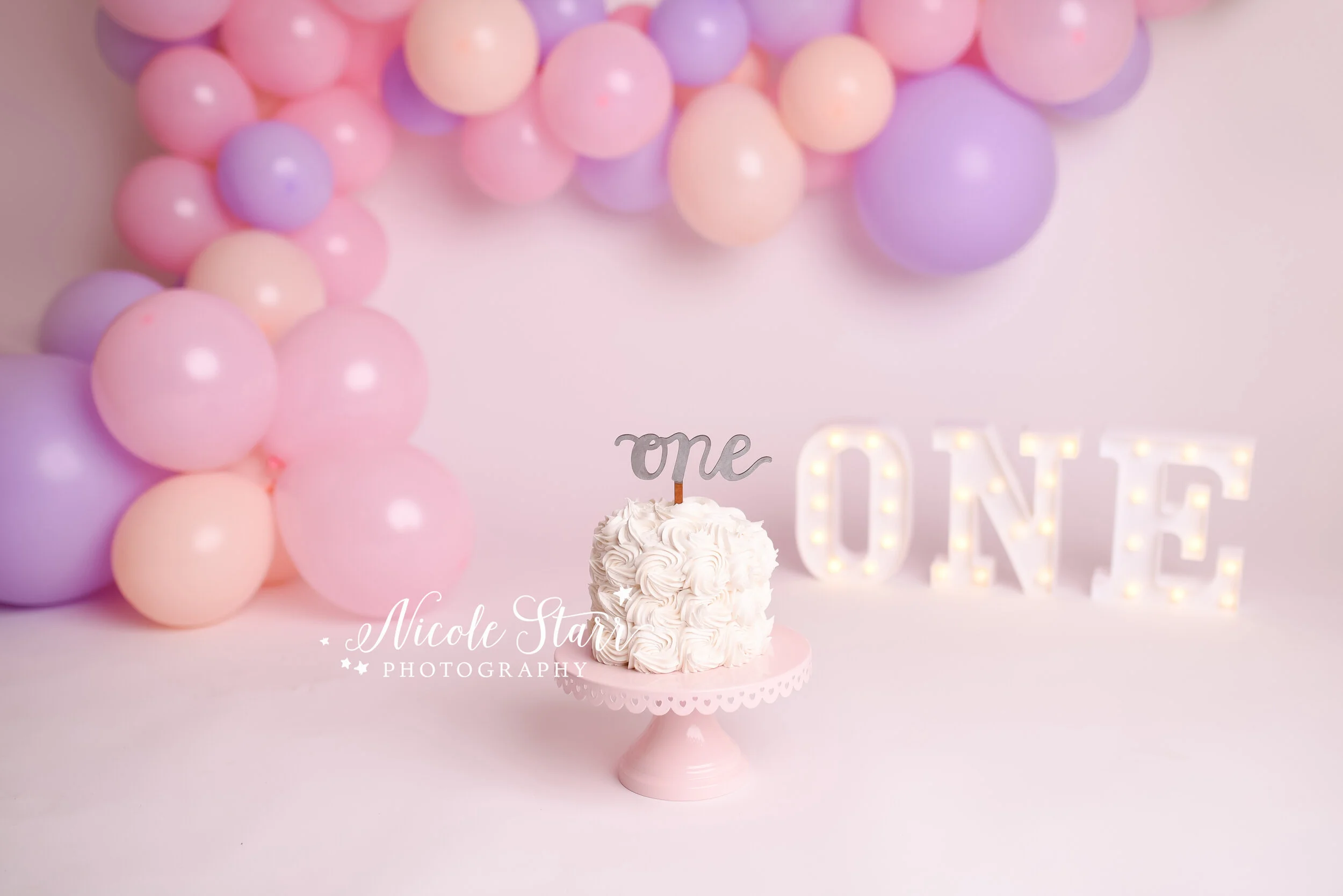 Pink, purple, and peach cake smash with balloon garland by Nicole Starr Photography | Saratoga Springs Cake Smash Photographer | Boston Cake Smash Photographer | Saratoga Springs Family Photographer | Boston Family Photographer Delmar NY Cake Smash …