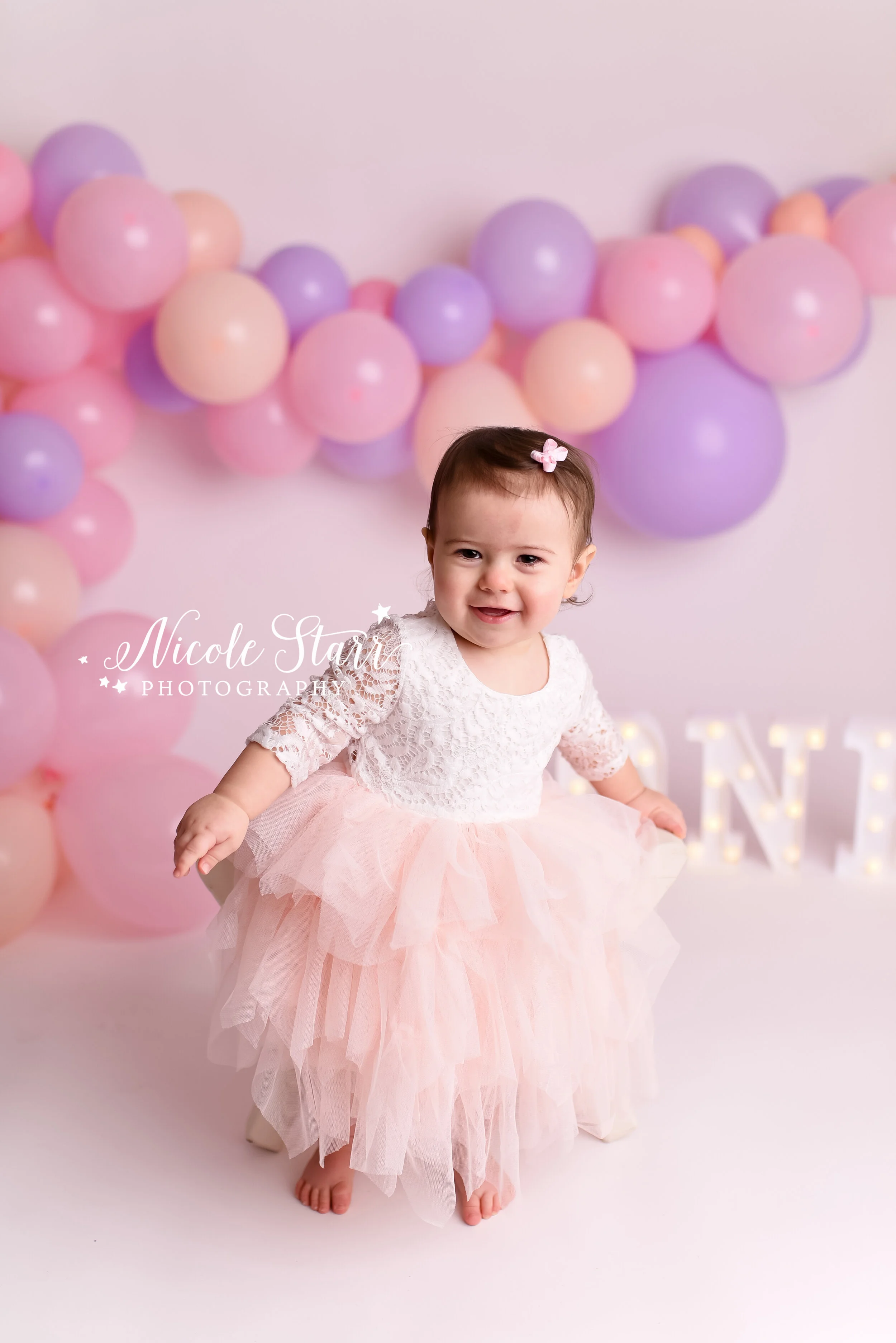 Pink, purple, and peach cake smash with balloon garland by Nicole Starr Photography | Saratoga Springs Cake Smash Photographer | Boston Cake Smash Photographer | Saratoga Springs Family Photographer | Boston Family Photographer Delmar NY Cake Smash …
