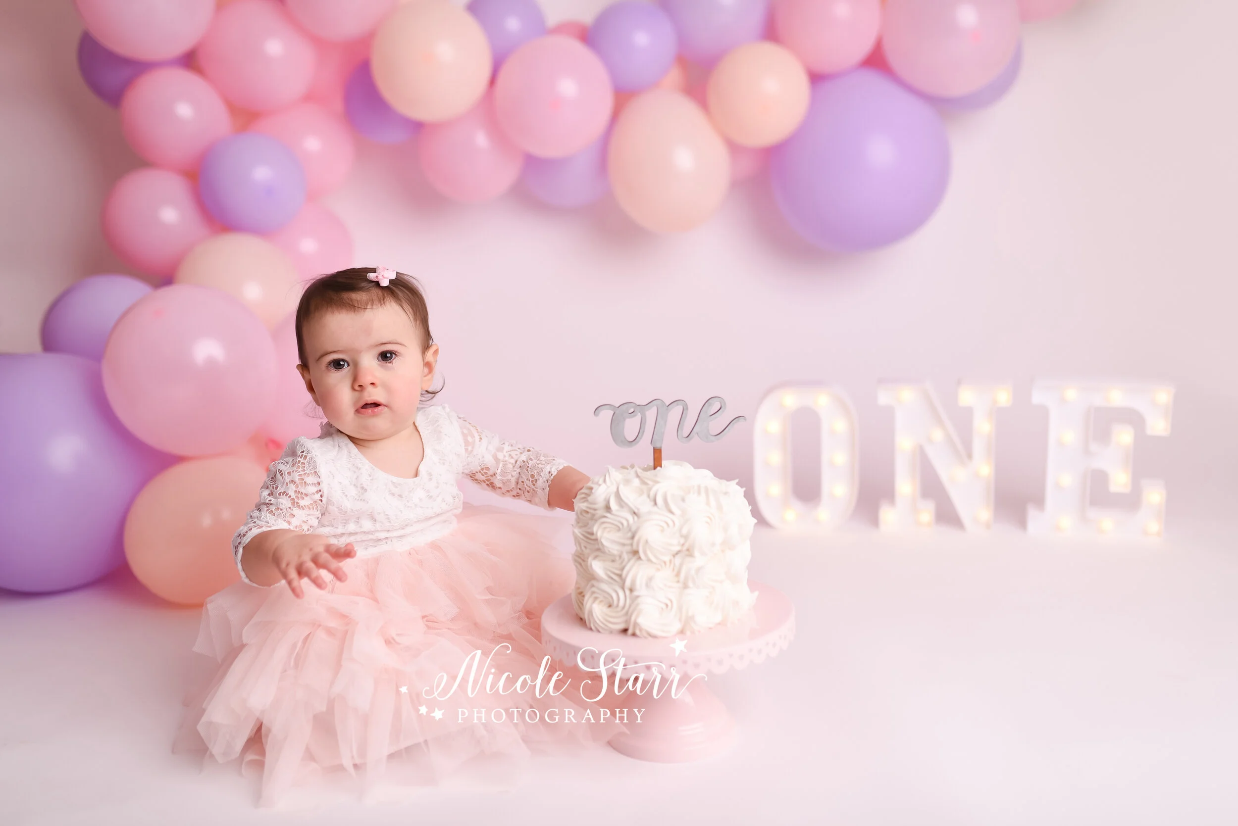 Pink, purple, and peach cake smash with balloon garland by Nicole Starr Photography | Saratoga Springs Cake Smash Photographer | Boston Cake Smash Photographer | Saratoga Springs Family Photographer | Boston Family Photographer Delmar NY Cake Smash …
