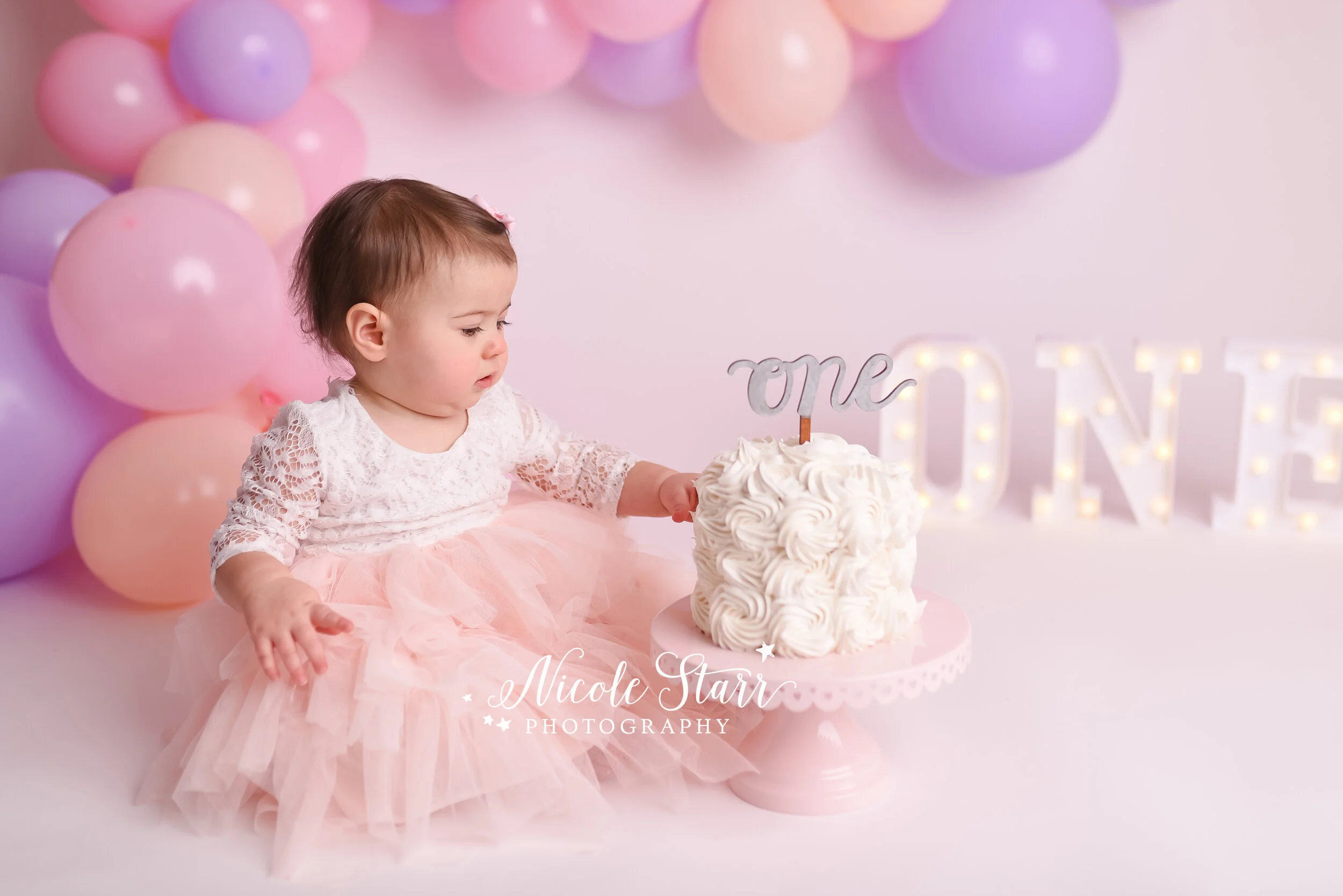 Pink, purple, and peach cake smash with balloon garland by Nicole Starr Photography | Saratoga Springs Cake Smash Photographer | Boston Cake Smash Photographer | Saratoga Springs Family Photographer | Boston Family Photographer Delmar NY Cake Smash …