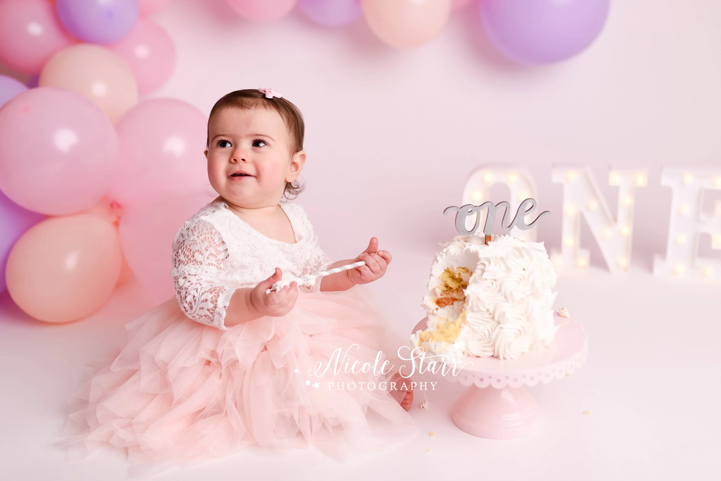Pink, purple, and peach cake smash with balloon garland by Nicole Starr Photography | Saratoga Springs Cake Smash Photographer | Boston Cake Smash Photographer | Saratoga Springs Family Photographer | Boston Family Photographer Delmar NY Cake Smash …