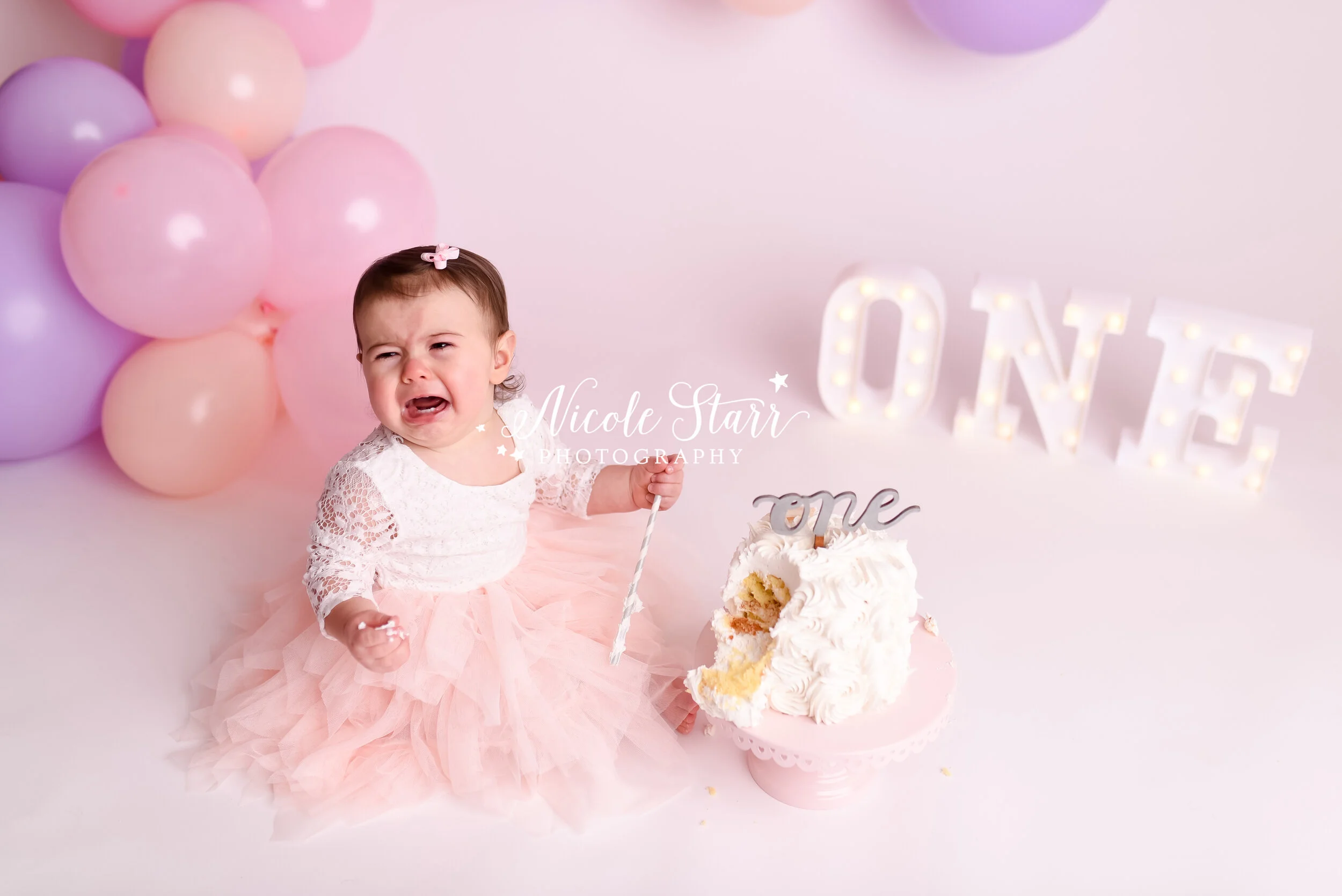 Pink, purple, and peach cake smash with balloon garland by Nicole Starr Photography | Saratoga Springs Cake Smash Photographer | Boston Cake Smash Photographer | Saratoga Springs Family Photographer | Boston Family Photographer Delmar NY Cake Smash …