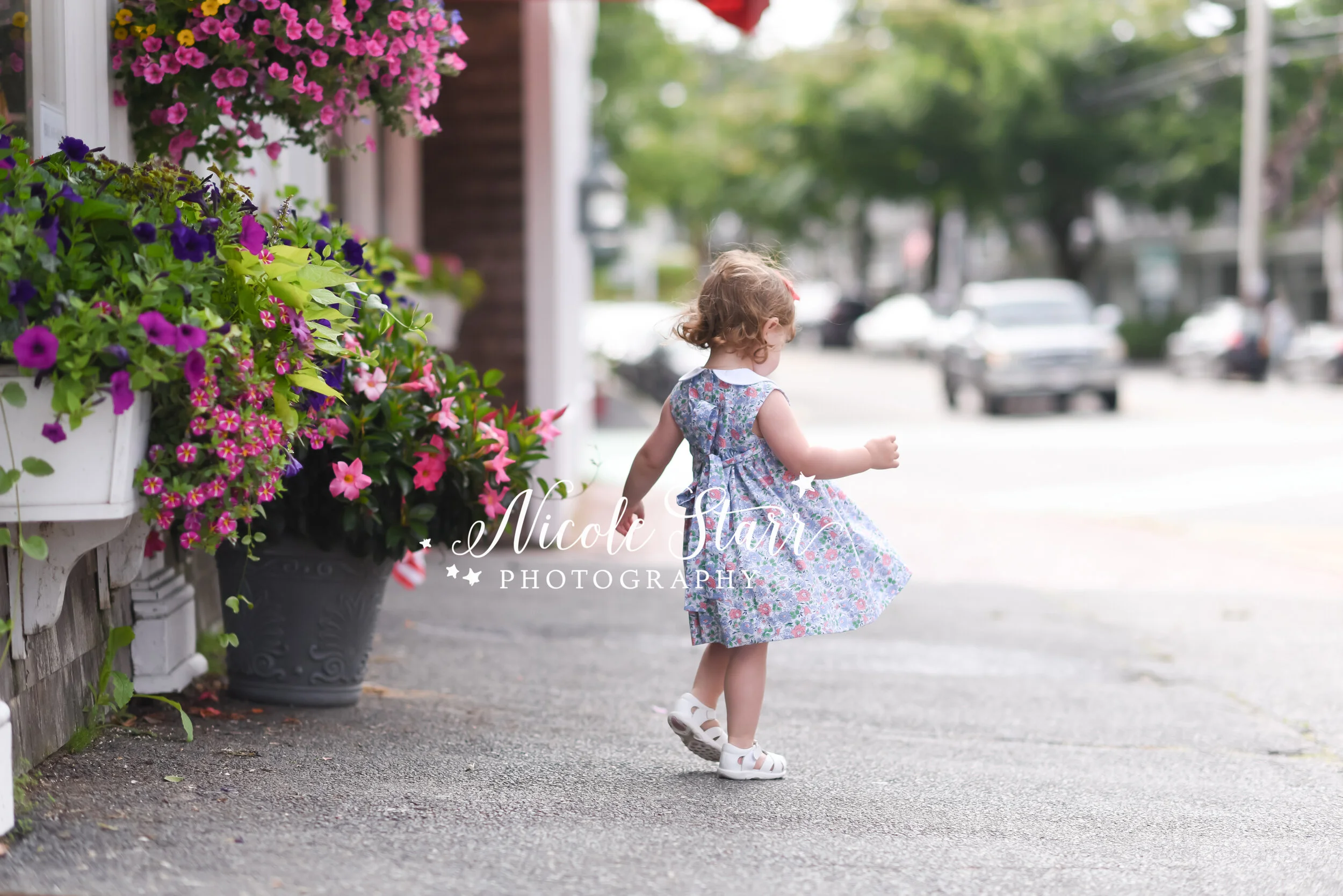 little girl in blue and pink dress twirls on sidewalk in Downtown Chatham photographed by Cape Cod family and beach photographer Nicole Starr Photography | Classic Cape Cod portraits
