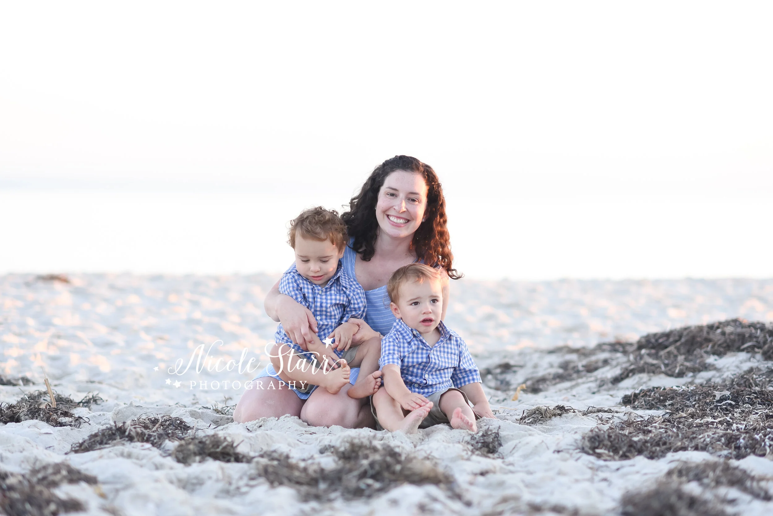 mom sits on sand holding sons photographed by Cape Cod family photographer Nicole Starr Photography