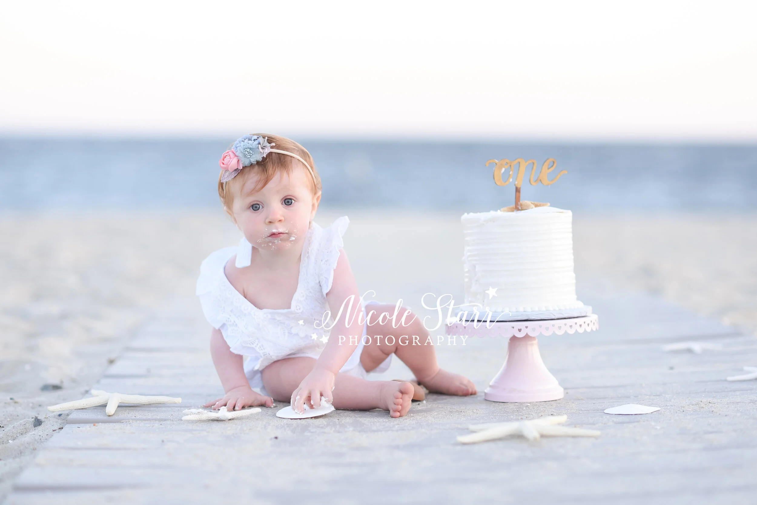 toddler girl crawls around cake on boardwalk photographed by Cape Cod family and cake smash photographer Nicole Starr Photography&nbsp;
