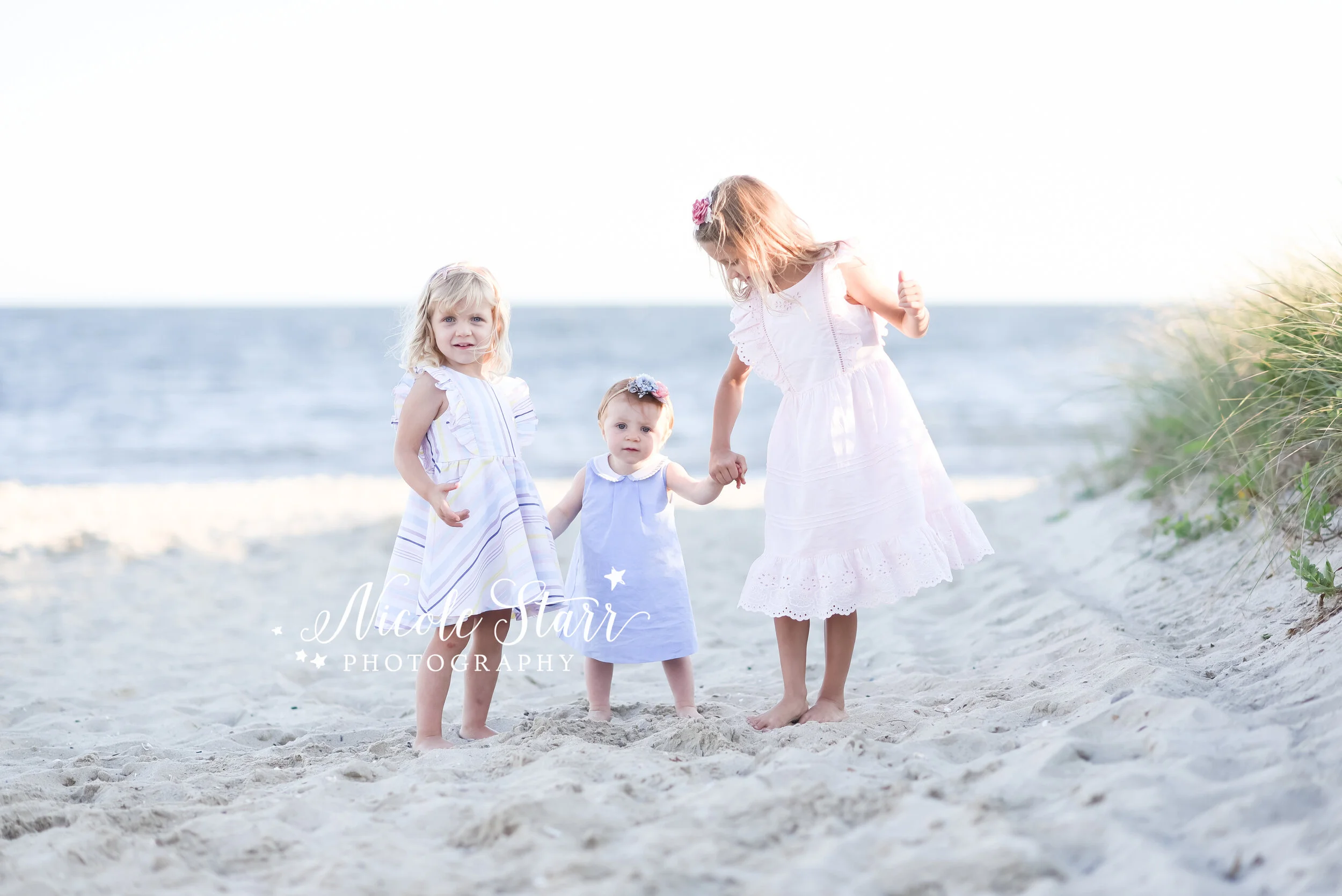 sisters walk through sand on beach during family photos with Cape Cod beach family photographer Nicole Starr Photography