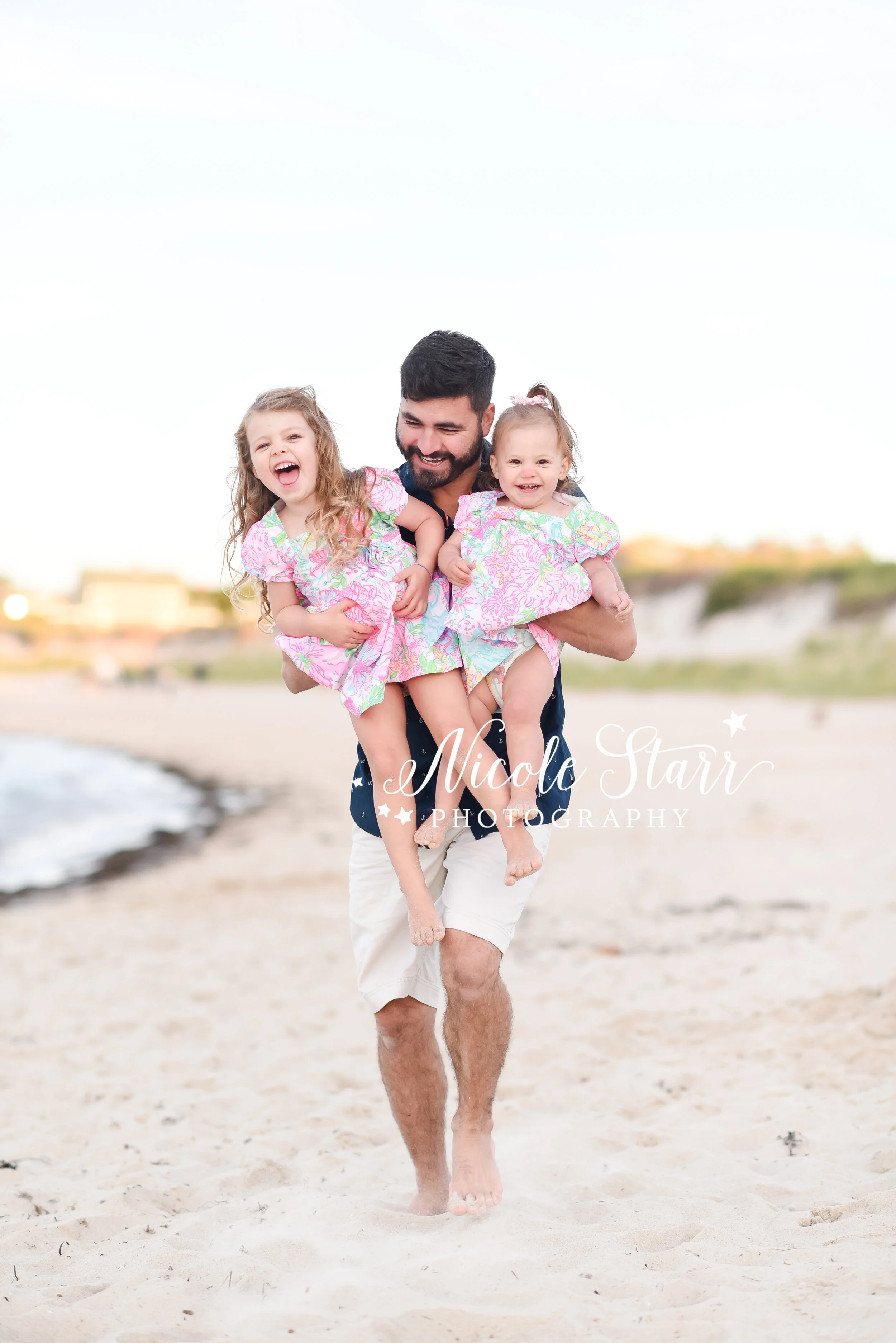 dad lifts girls during family photos on beach with Cape Cod family photographer Nicole Starr Photography