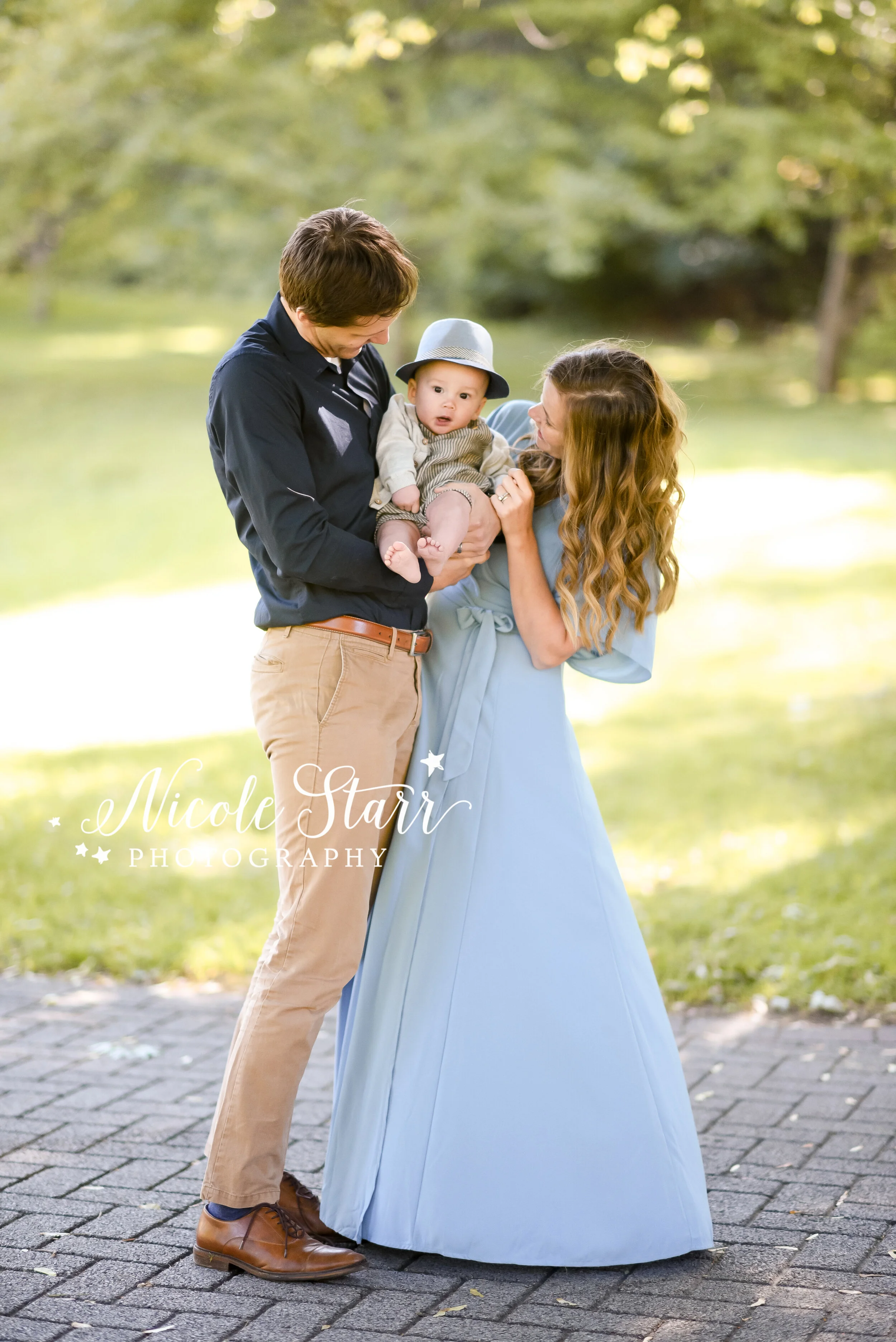 parents look at baby boy in hat during Congress Park family photos with Saratoga Springs and Delmar NY family photographer Nicole Starr Photography