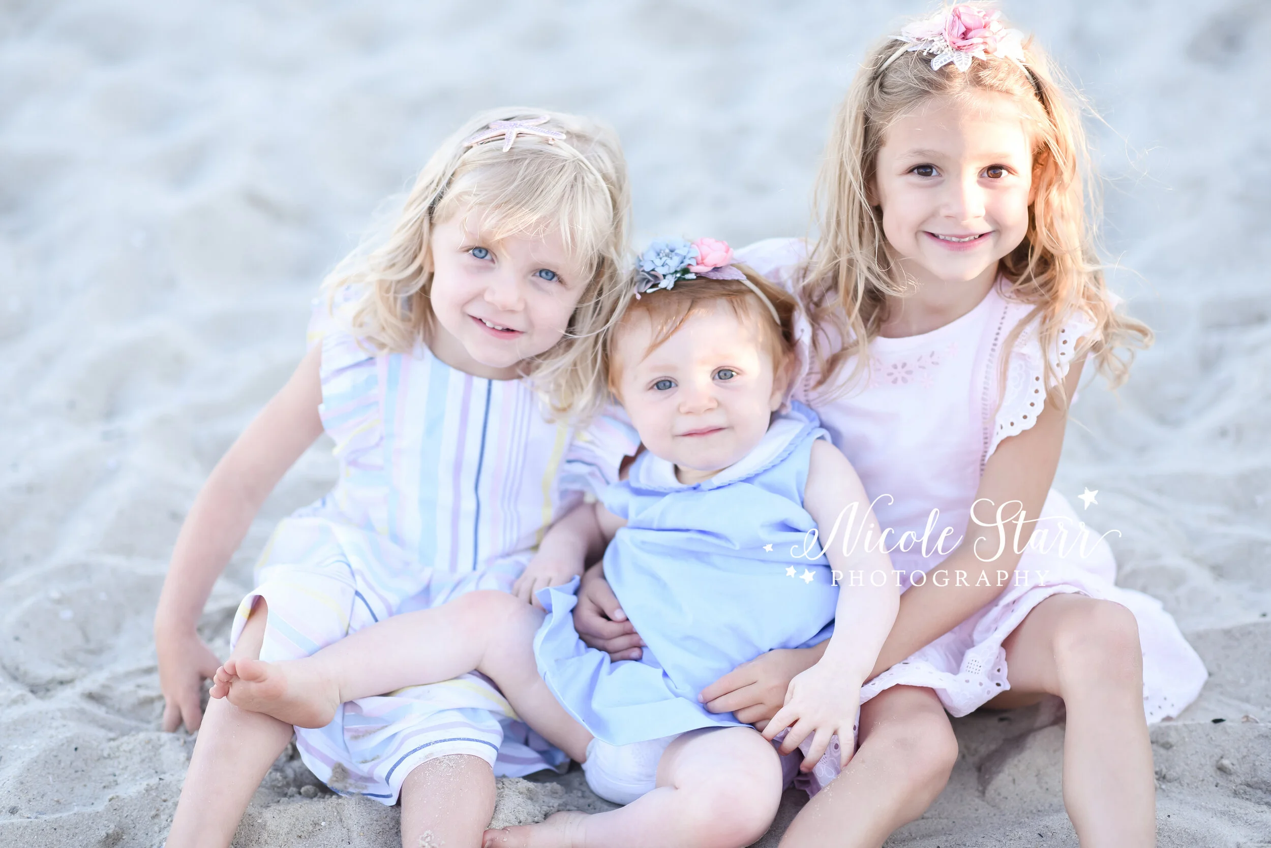 three siblings sit on sand during Cape Cod family photos with Saratoga Springs luxury portrait photographer Nicole Starr Photography