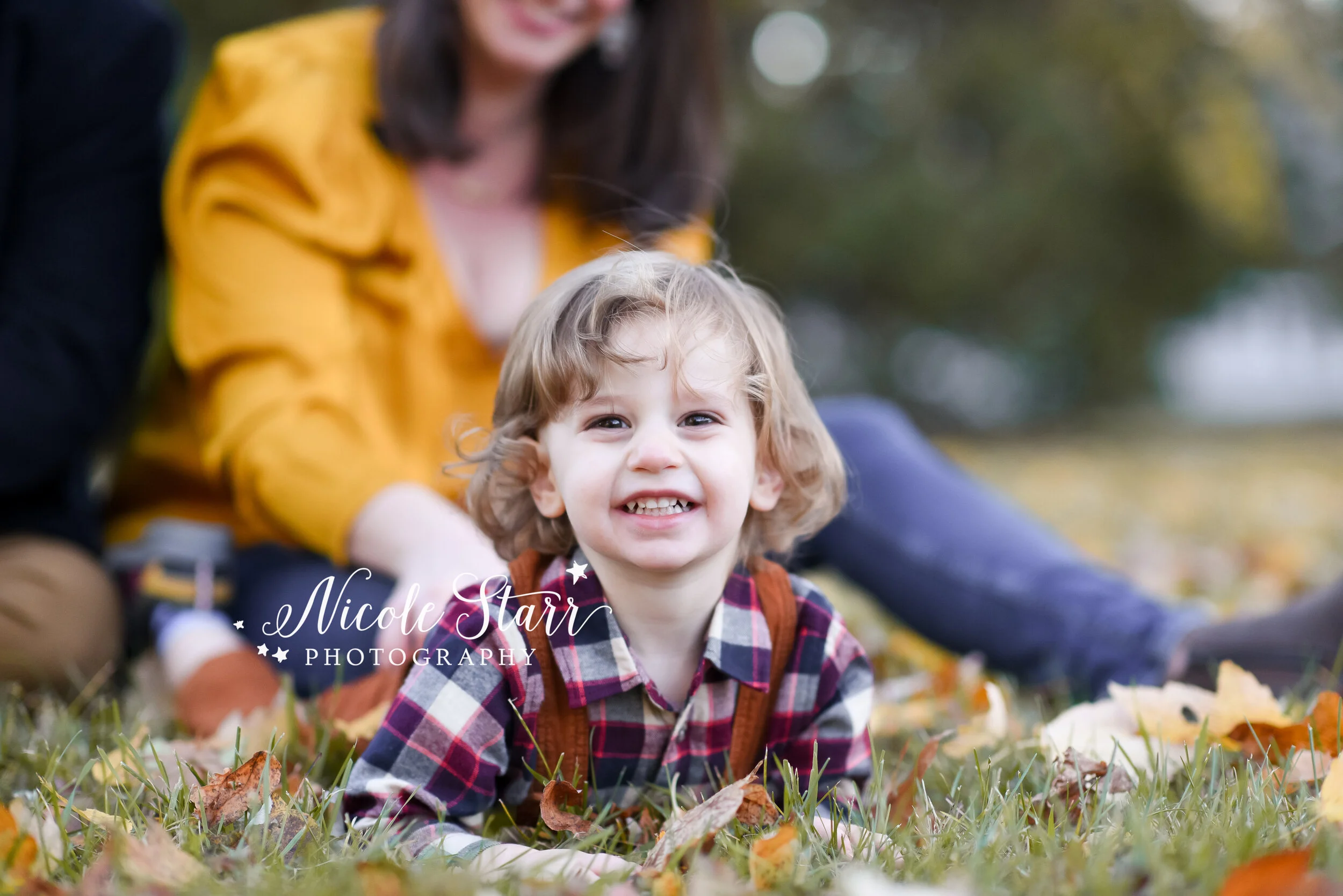 toddler plays in leaves during family photos with Delmar NY family photographer Nicole Starr Photography
