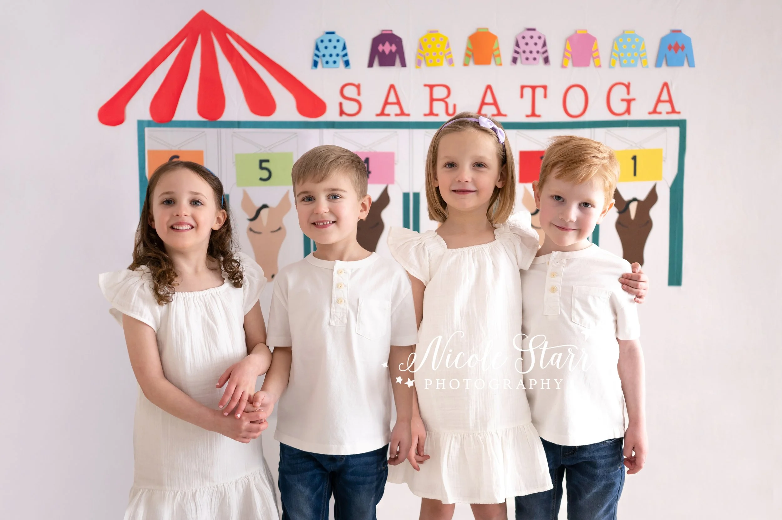 four five-year olds pose in front of Saratoga Springs racetrack backdrop in Saratoga Springs NY studio with Nicole Starr Photography