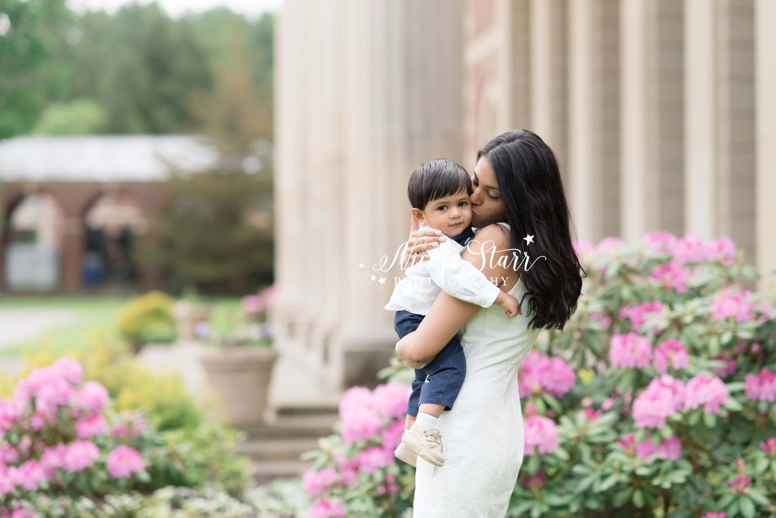 mom kisses son outside Hall of Springs in Saratoga Springs during spring family photos with Nicole Starr Photography
