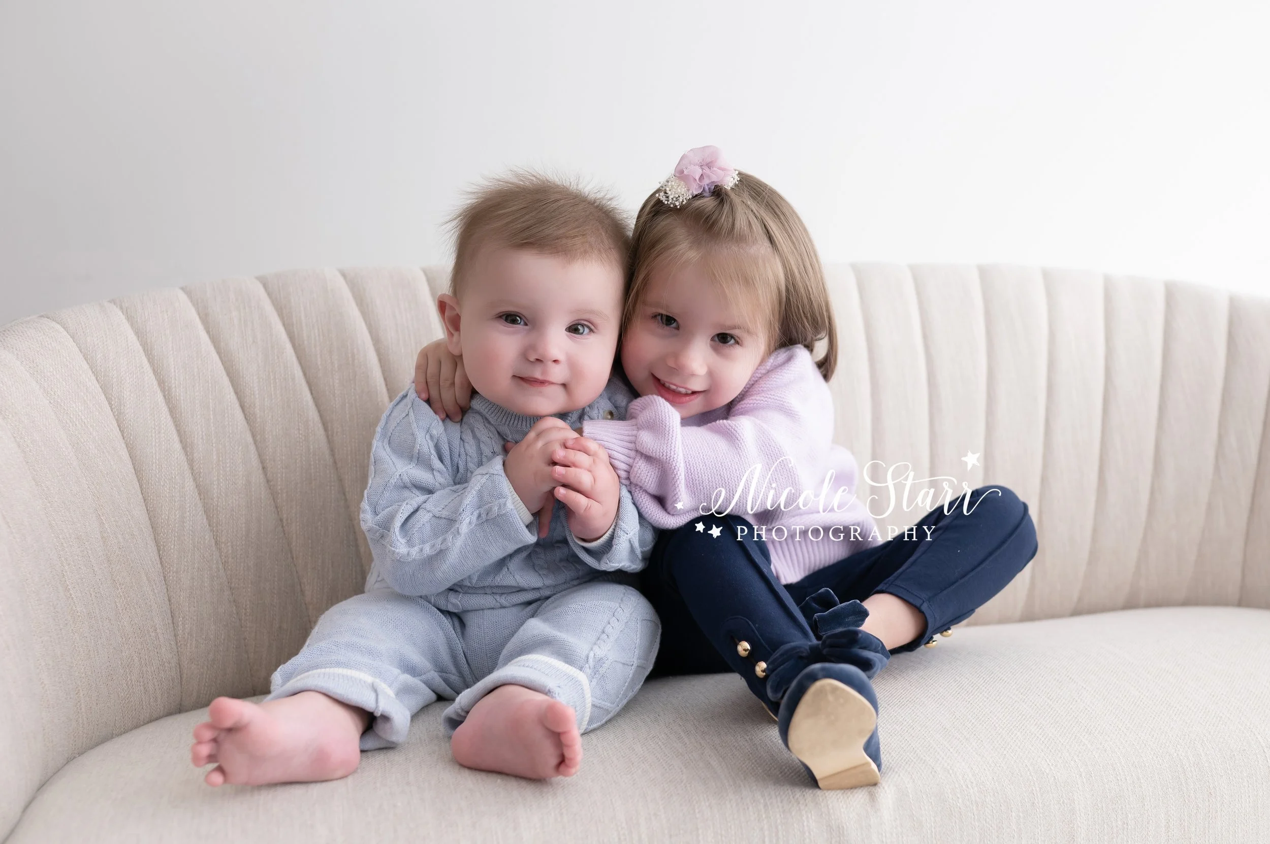 little girl in purple sweater hugs younger brother in blue jumper during family portraits with Nicole Starr Photography