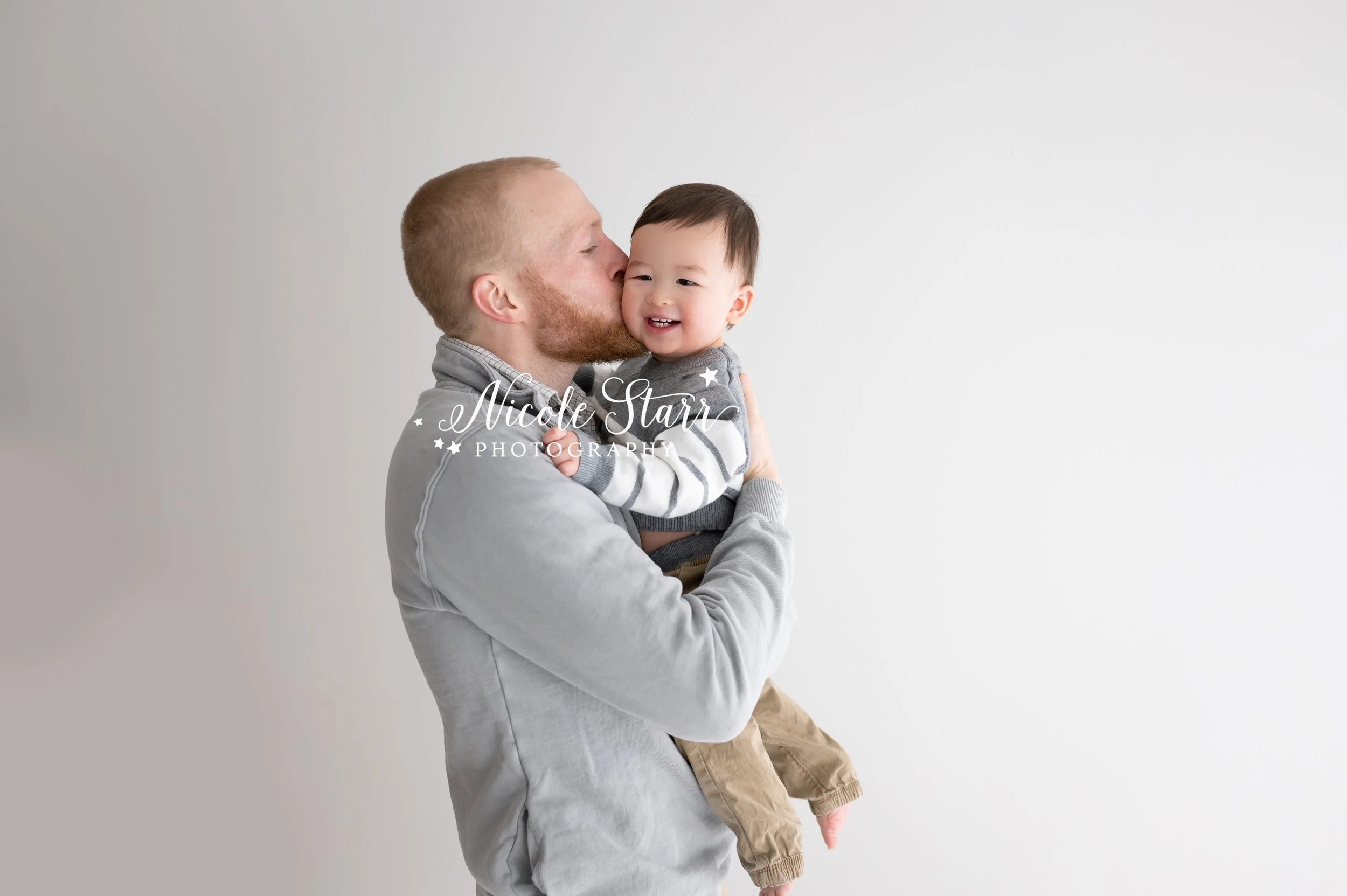 dad kisses son in studio during milestone portraits with  Saratoga Springs NY family photographer Nicole Starr Photography