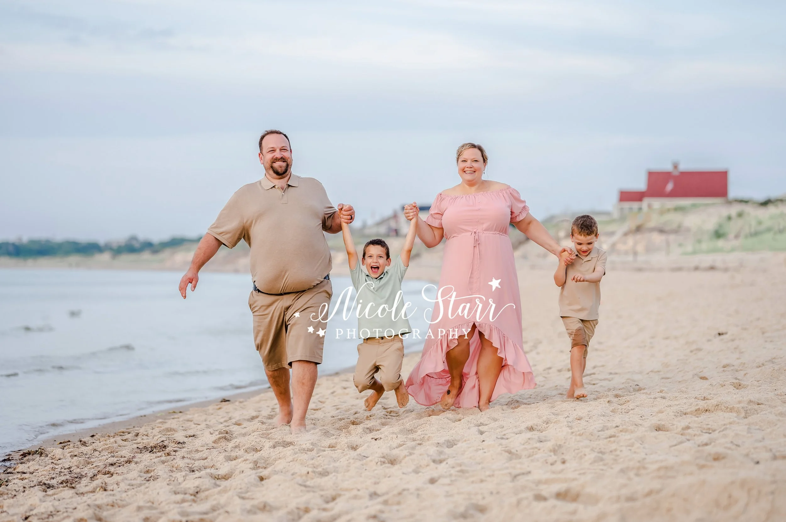 family holds hands walking on beach along water during summer family portraits with MA beach photographer Nicole Starr Photography