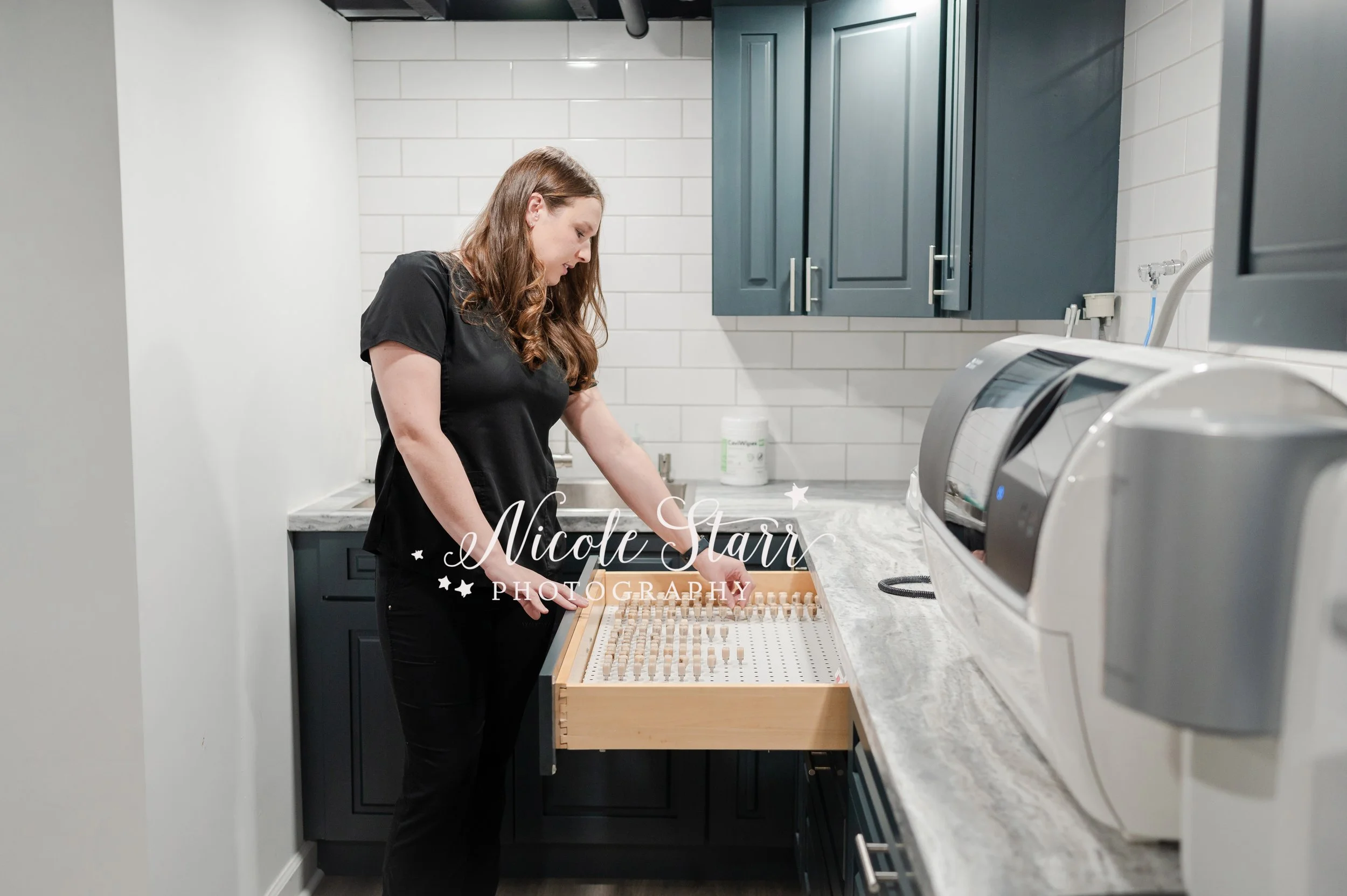 dentist looks at plastic teeth in pegboard during branding session in dental office photographed by Clifton Park branding photographer Nicole Starr Photography