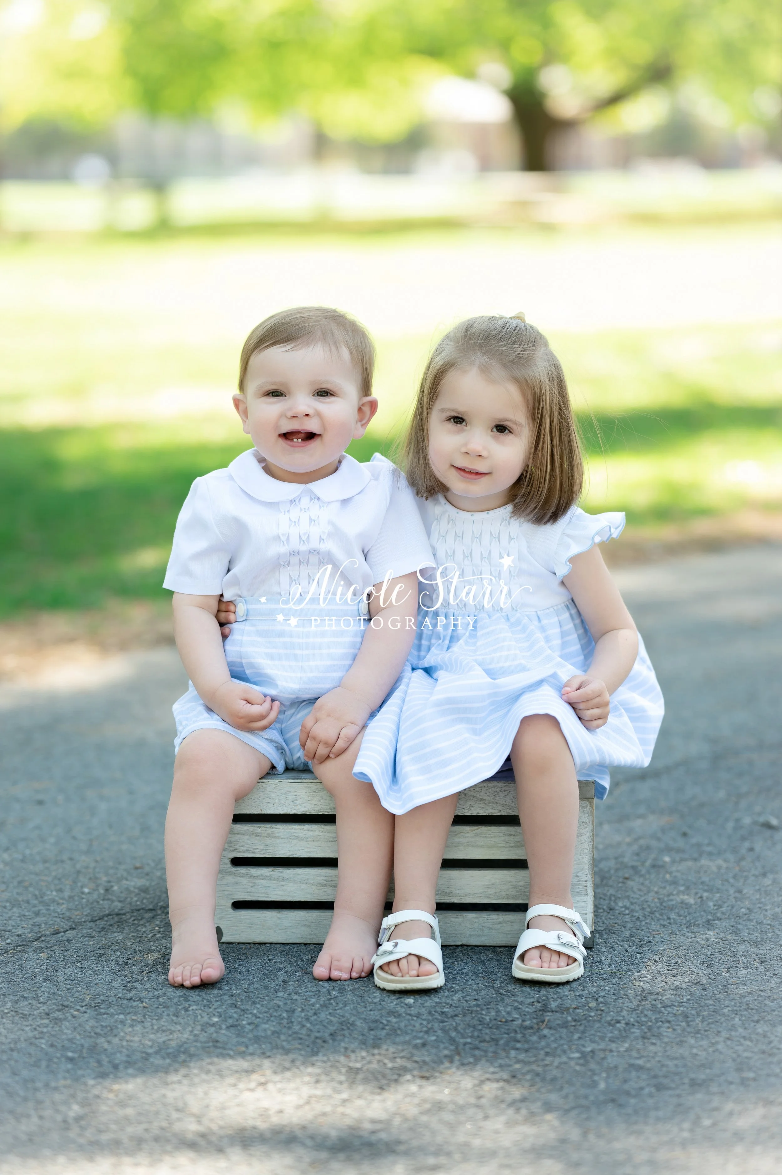 siblings sit on wooden crate during family photos at the Hall of Springs with Saratoga Springs NY family photographer Nicole Starr Photography