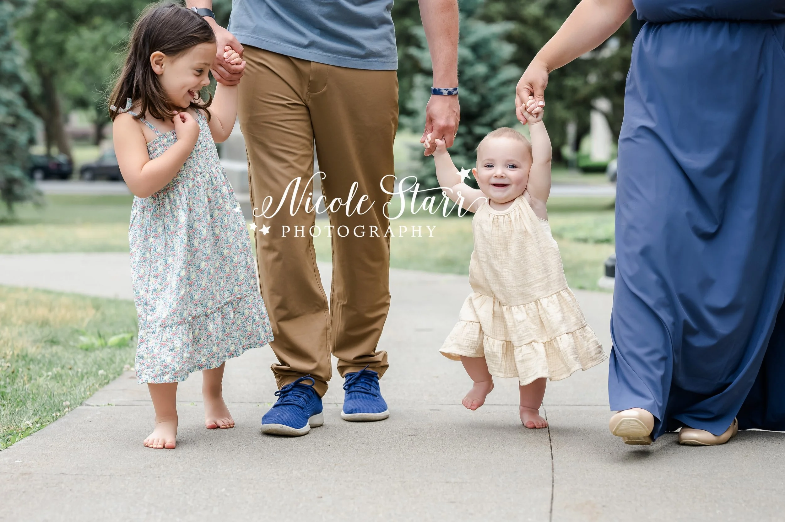 family of four holds hands in blue and tan outfits during family portraits in Congress Park photographed by Saratoga Springs family photographer Nicole Starr Photography