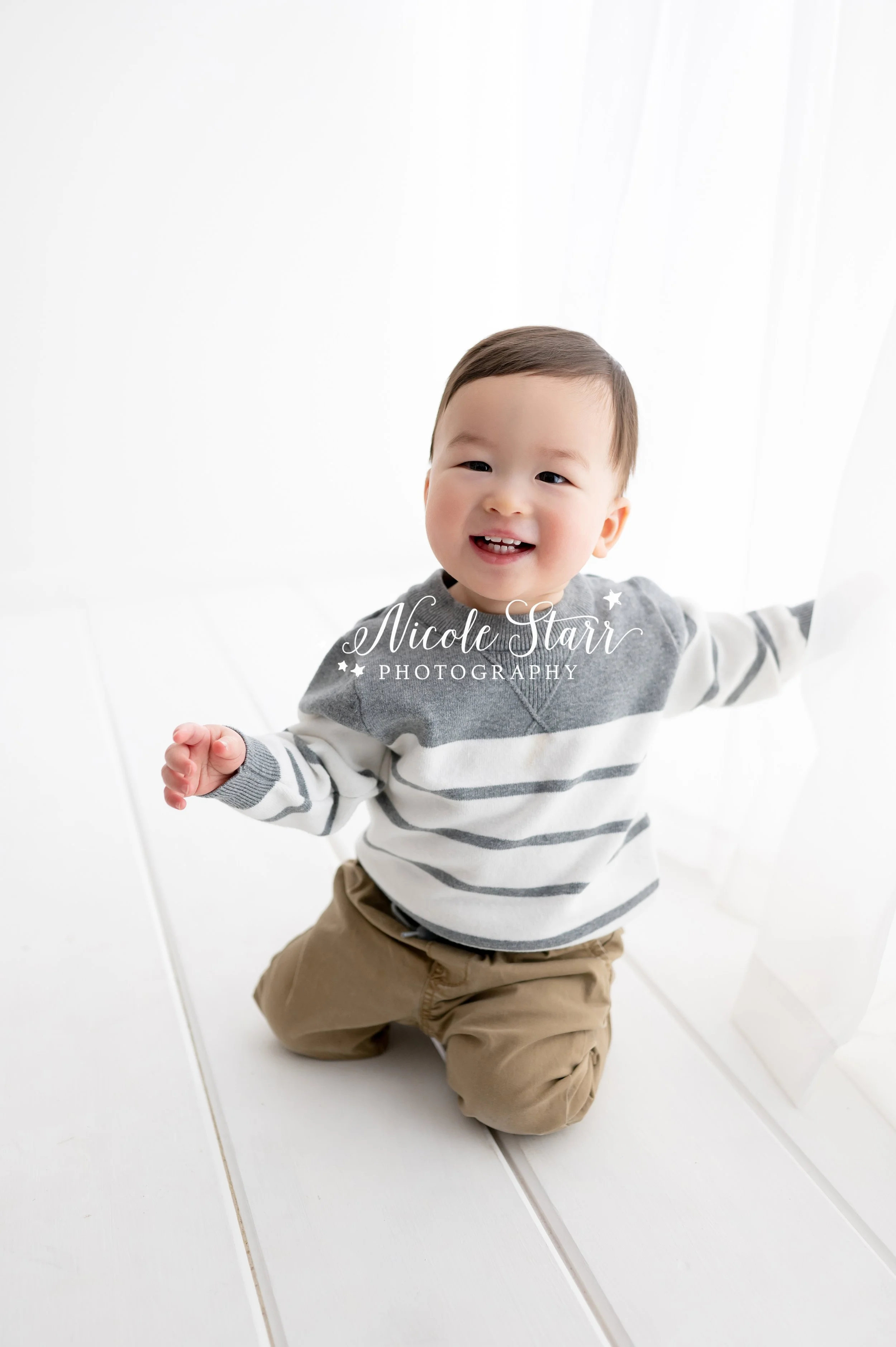 toddler plays on white studio floor during milestone portraits with Saratoga Springs NY family photographer Nicole Starr Photography