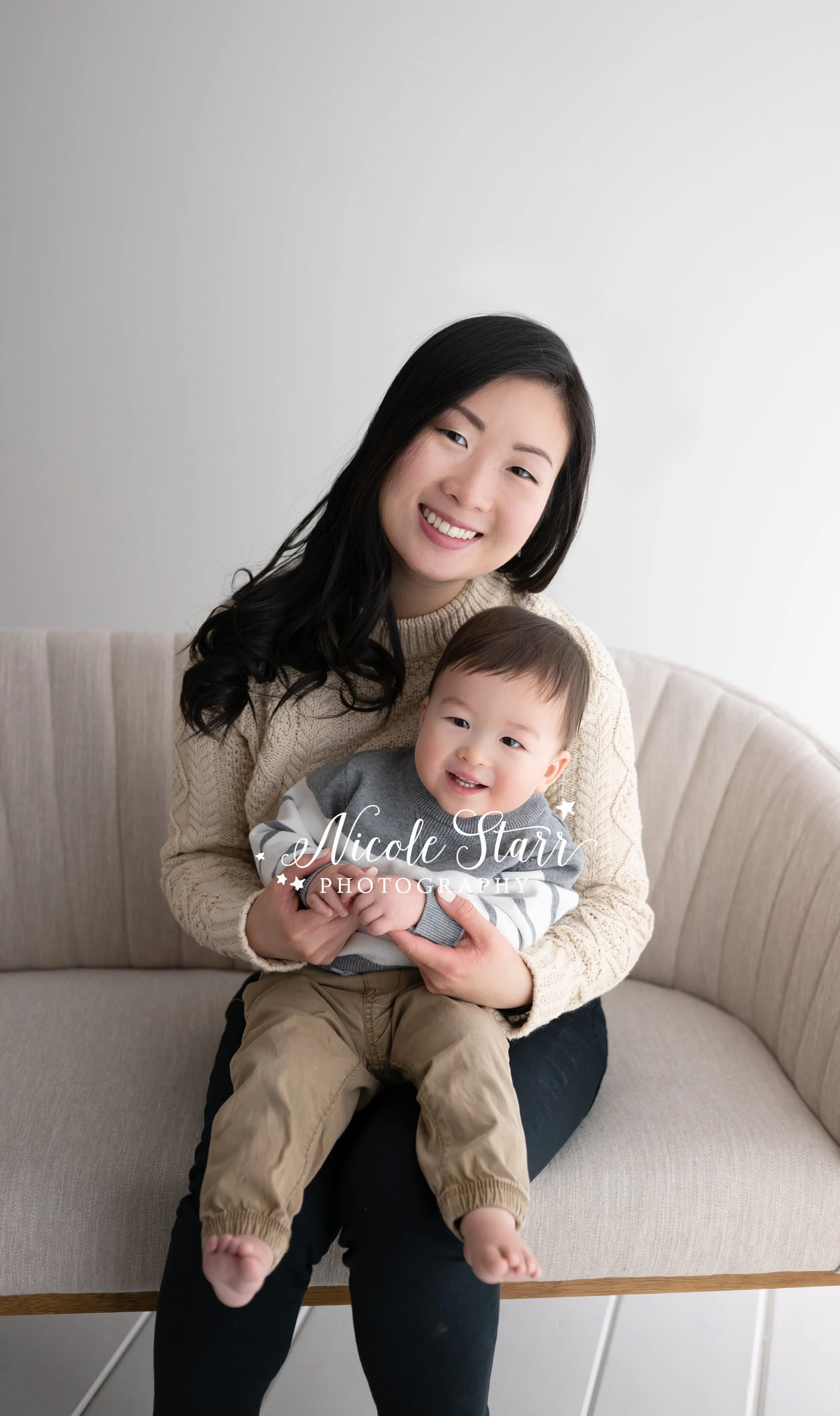 mom sits on sofa with toddler during studio portraits with Saratoga Springs NY family photographer Nicole Starr Photography