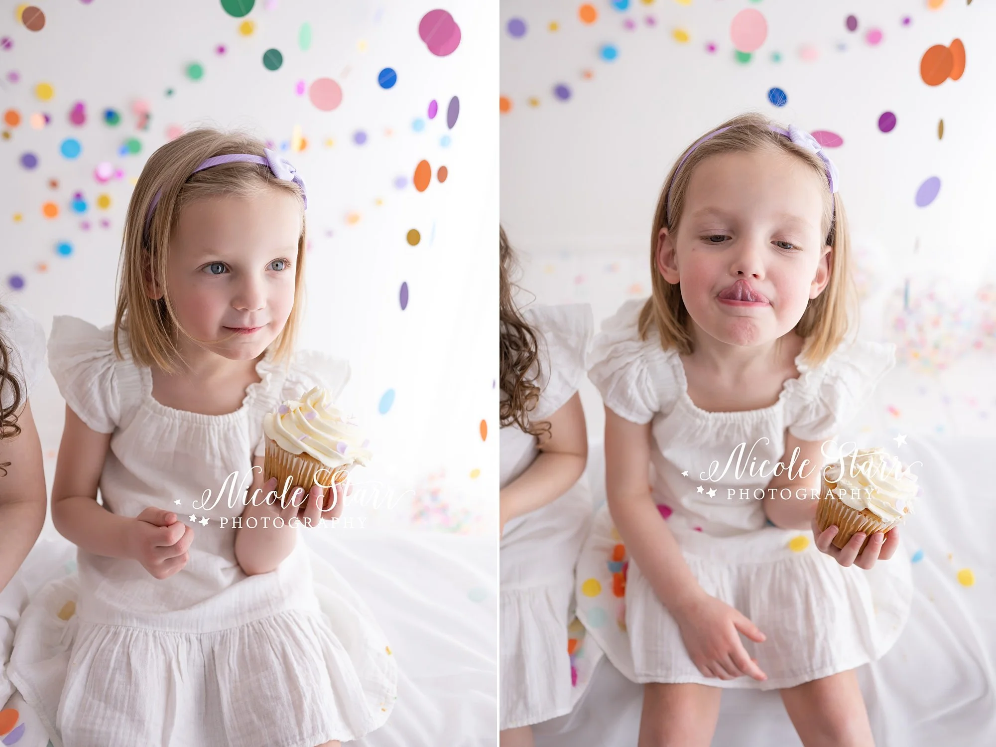 blonde girl with purple bow in white dress eats cupcake and licks icing off her nose in studio with rainbow streamers for cake smash with Nicole Starr Photography, Saratoga Springs children’s photographer