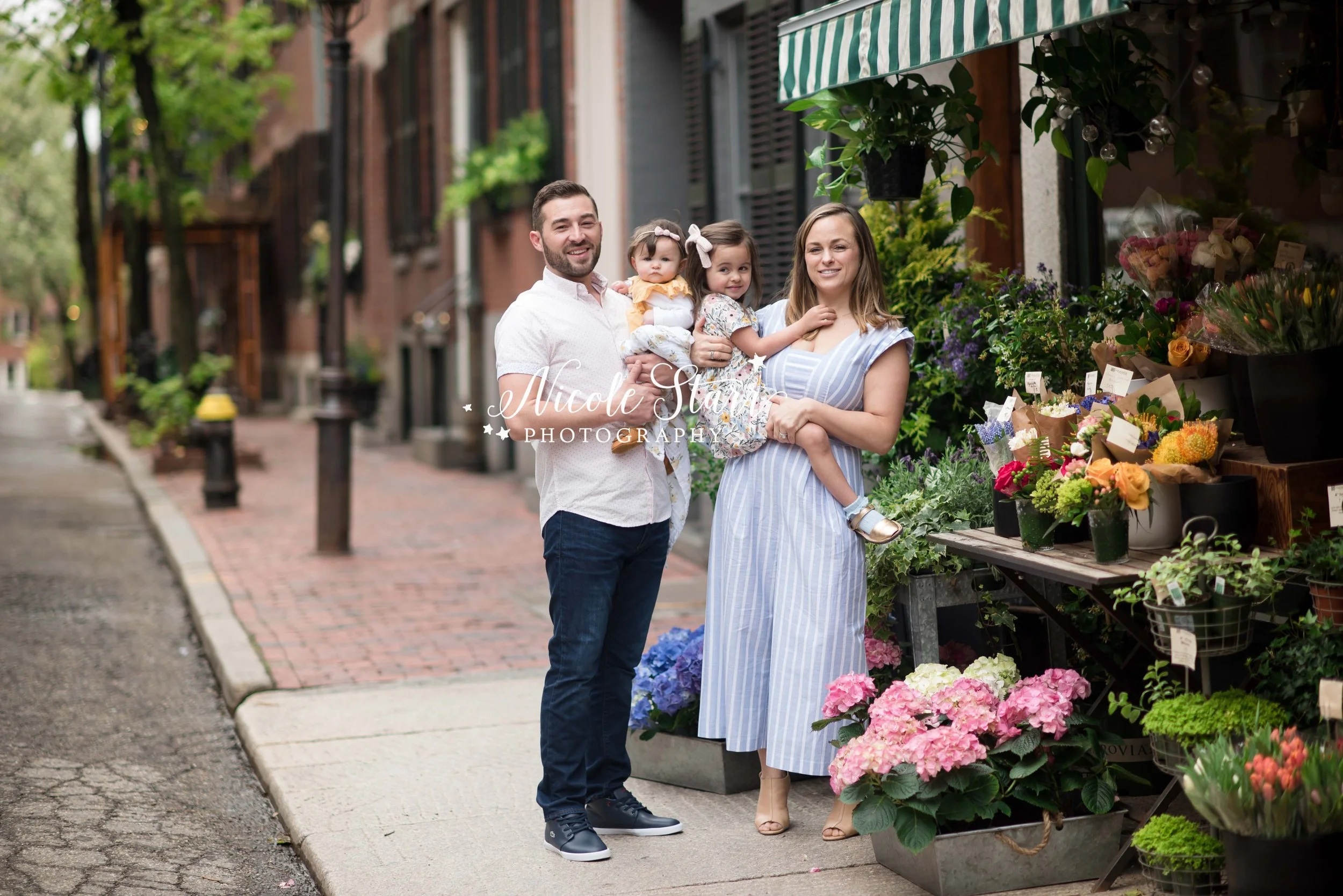 parents pose with toddlers on street with flowers photographed in Saratoga Springs NY with Nicole Starr Photography