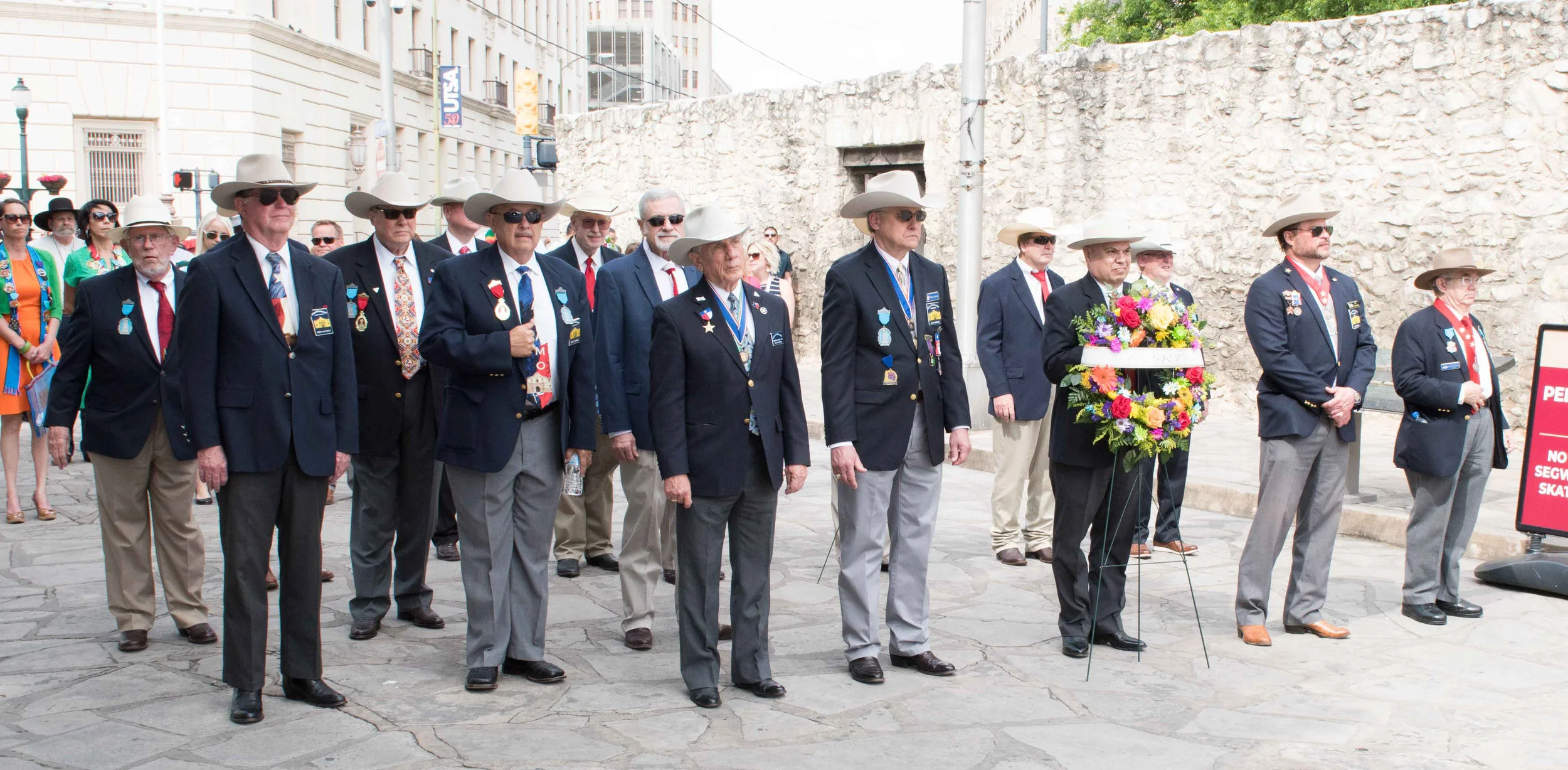 ( left to right ) SRT 1st Vice President General Ken Pfeiffer , President General Ed Heath , Alamo Chapter President John Meehan , Secretary Joe Ramirez , Past President Jason Chall & Administrator for Educational Events Bob Benavides wait to be called to the place a wreath in front of the Alamo at the annual Pilgrimage to The Alamo on Alamo Plaza. Every year since 1925, the Alamo Mission Chapter of the Daughters for the Republic of Texas (DRT) has staged the annual Pilgrimage to the Alamo & The Sons Of The Republic of Texas, Alamo Chapter was there to show its support. This is a memorial tribute to the Alamo Heroes and the heritage of Texas. A solemn wreath bearing procession of historic, civic, patriotic, military and school groups depart from the Vietnam Memorial at the Tobin Center, at 3:30 p.m., and walk silently to the Alamo. Simultaneously, an authoritative voice intones the names of the Alamo defenders from inside the Alamo walls. Following the procession and placing of the wreaths on the Alamo greensward, a brief memorial service takes place. The Fiesta Military Coordinator delivers the address and the sounding of Taps ends the ceremony. The Alamo Mission Chapter, DRT, founded in 1905, exists to provide and protect the history of Texas. The Chapter perpetuates the memory of the men and women who achieved and maintained Texas Independence, encourages historical research and preservation, and celebrates Texas Honor Days.