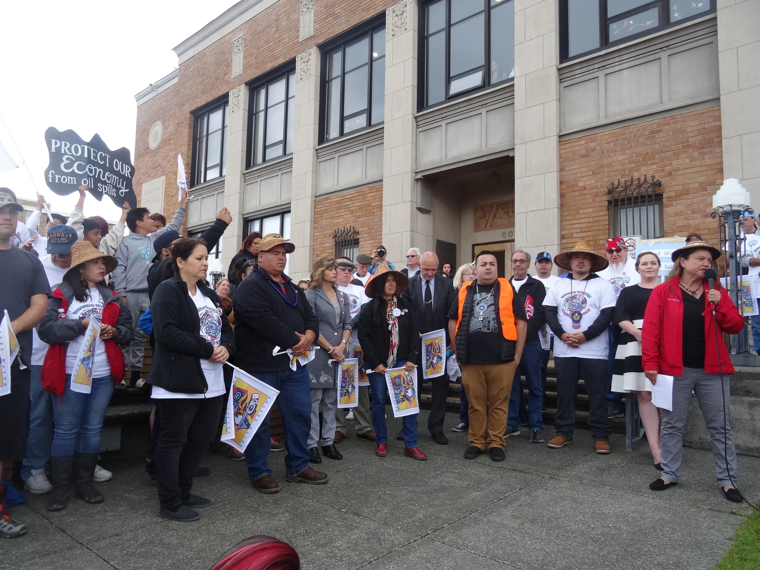 Quinault President Fawn Sharp (right) and Vice-President Tyson Johnston (5th from right) host the "Shared Waters, Shared Values" rally on July 8, 2016, with representatives from the Lummi, Quileute and Makah tribes, Hoquiam Mayor Jasmine Dickhoff (2nd from right), other local officials, and leaders of fishing associations and local environmental groups (Credit: Zoltan Grossman ).